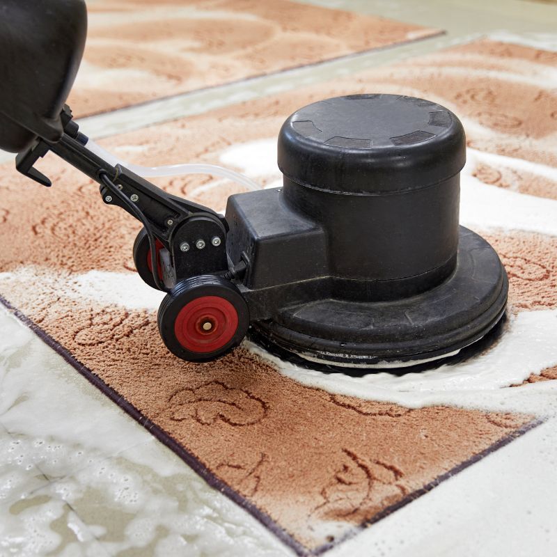 A person is using a machine to clean a rug