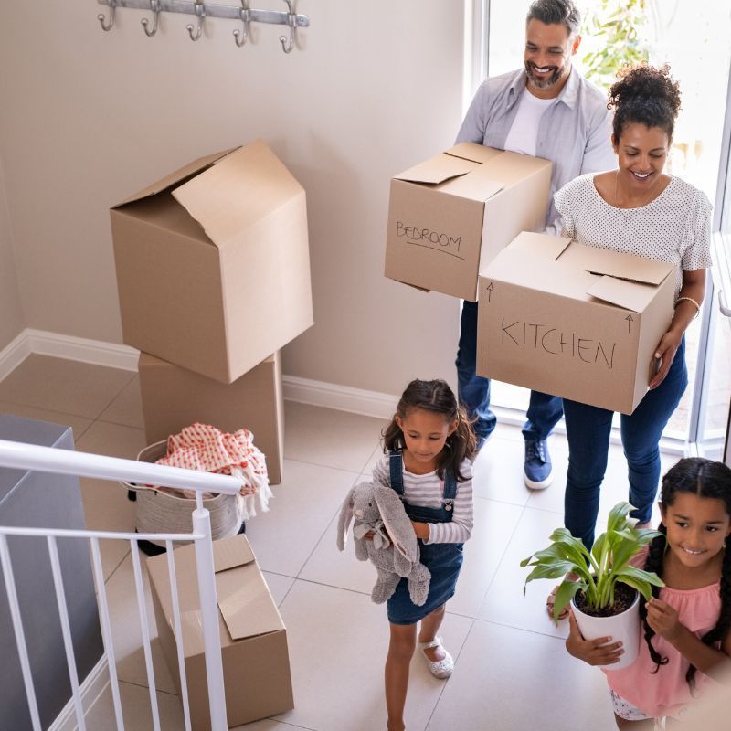 Family moving into a new home, carrying boxes labeled