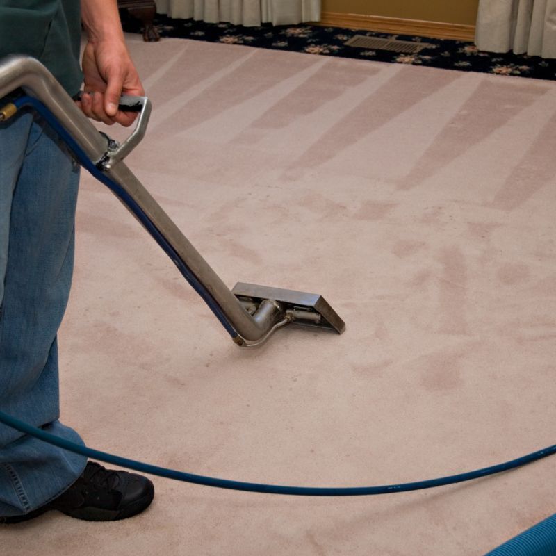 A man is using a vacuum cleaner to clean a carpet