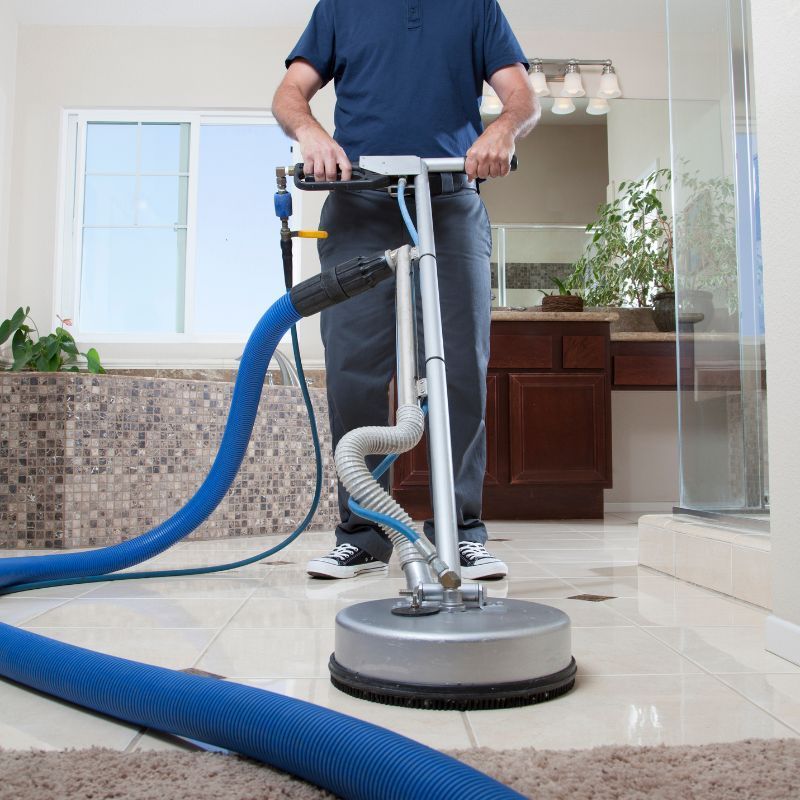 A man is using a machine to clean the floor in a bathroom