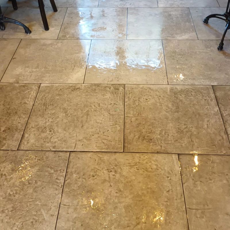 A close up of a tiled floor with tables and chairs in the background.