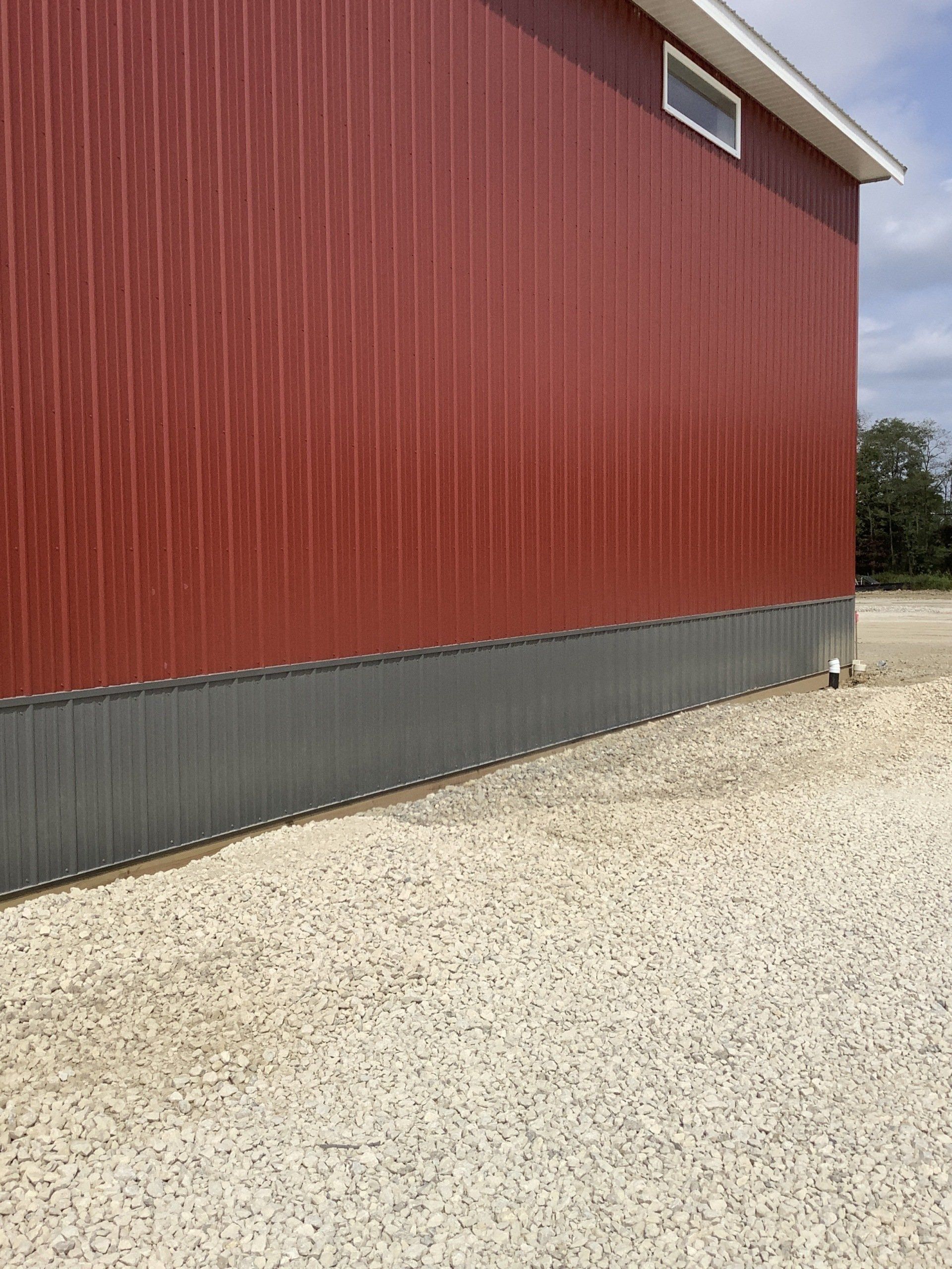 Red and gray barn exterior with gravel ground.