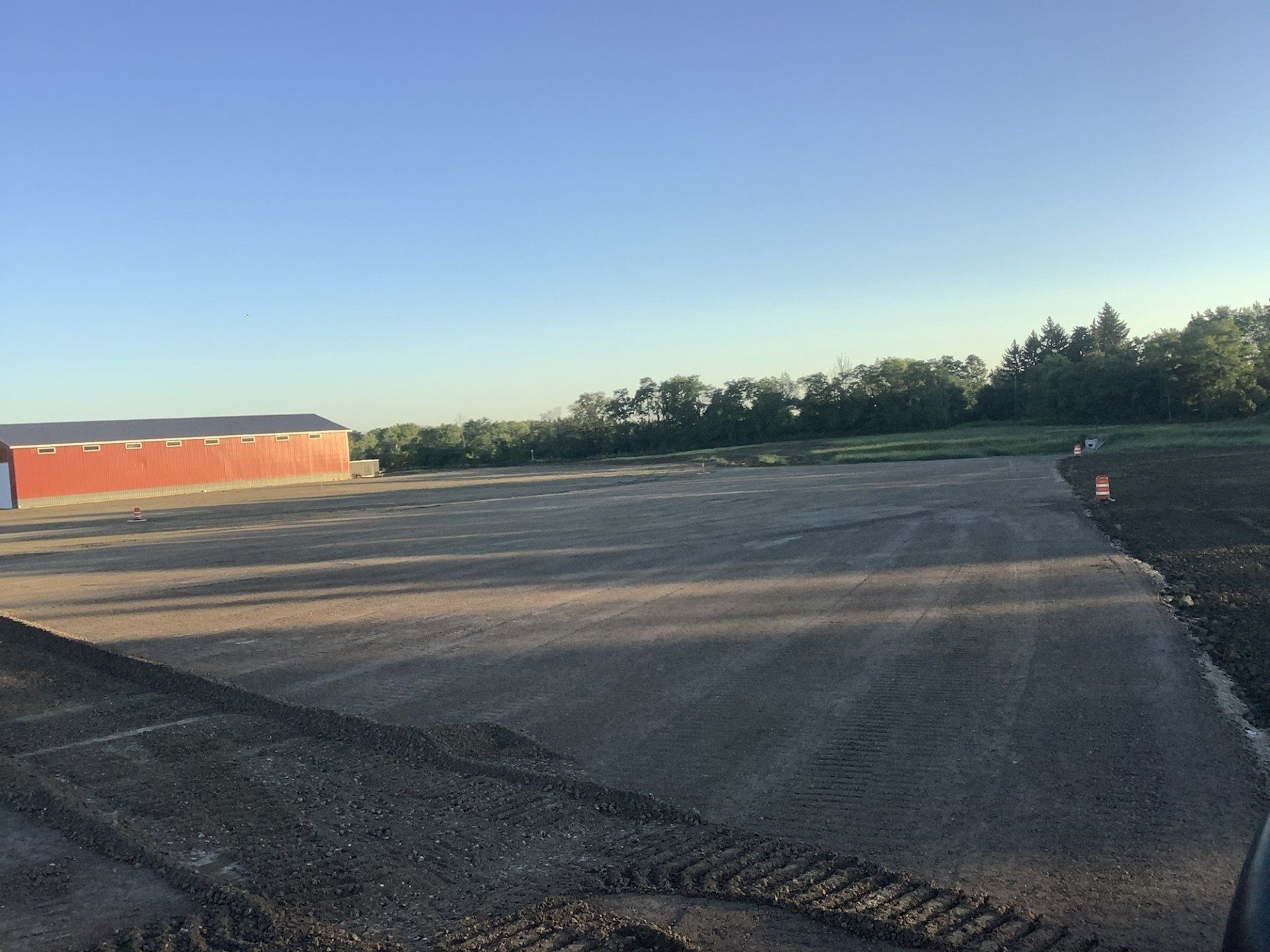 A large cleared area with a red barn in the background and trees along the horizon.