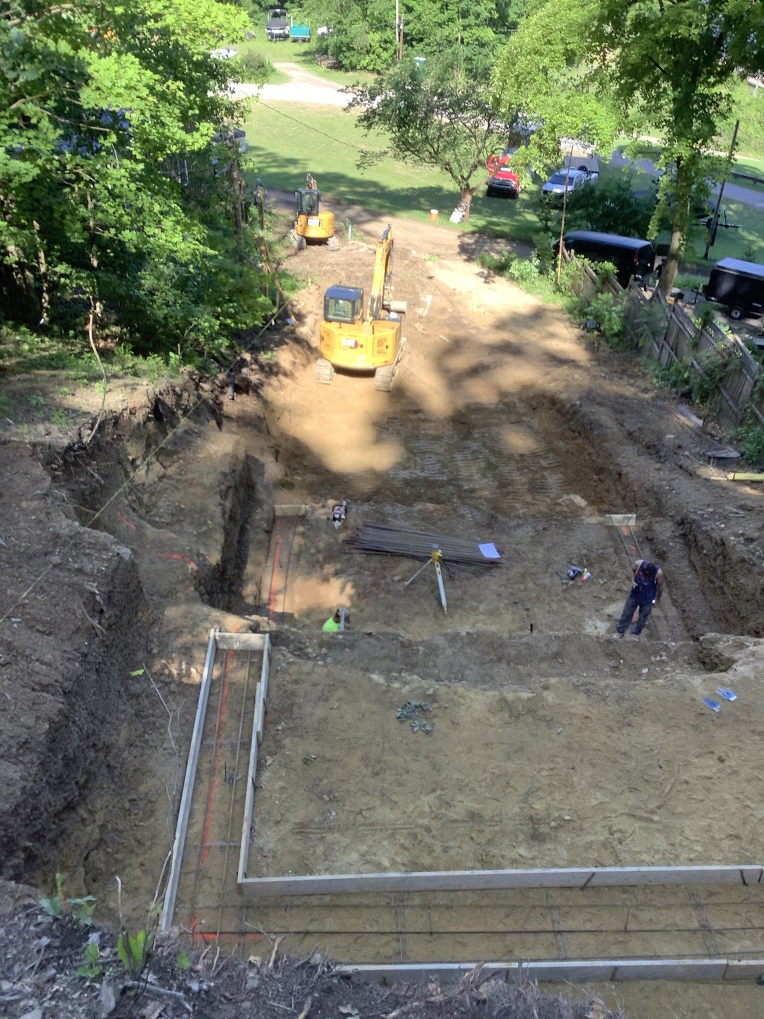 Construction site with excavators, a partially dug foundation, and workers.