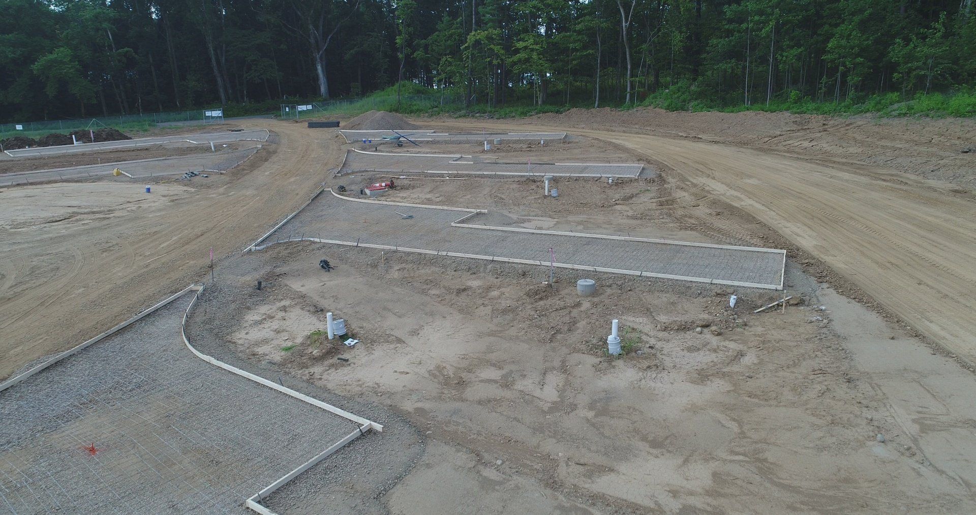 Dirt plots bordered by stones, set in a field with trees in the background.