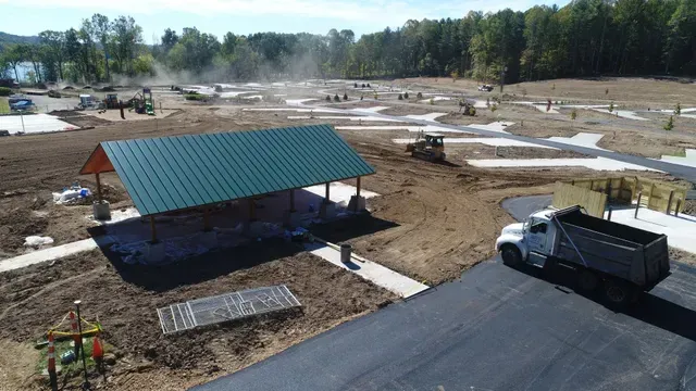 Construction site with a covered shelter and dump truck; earthmoving equipment in background.