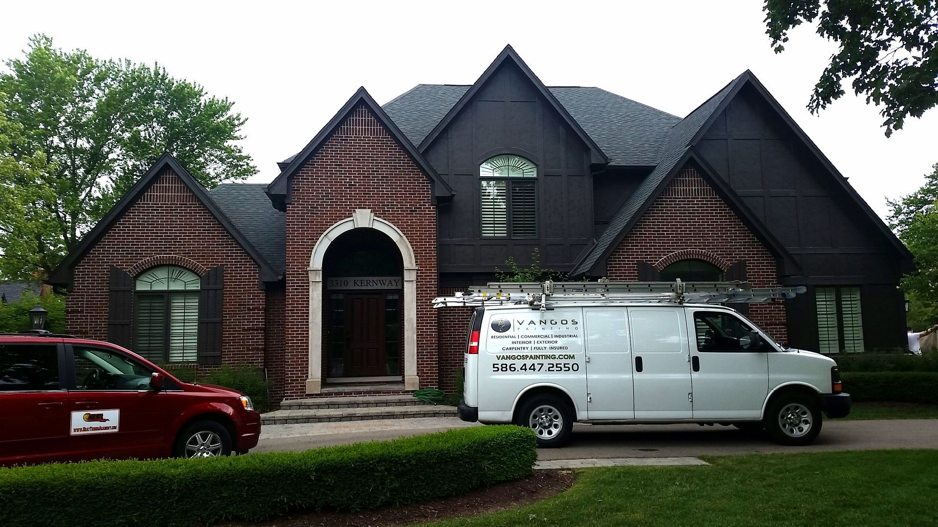 A white van is parked in front of a large brick house