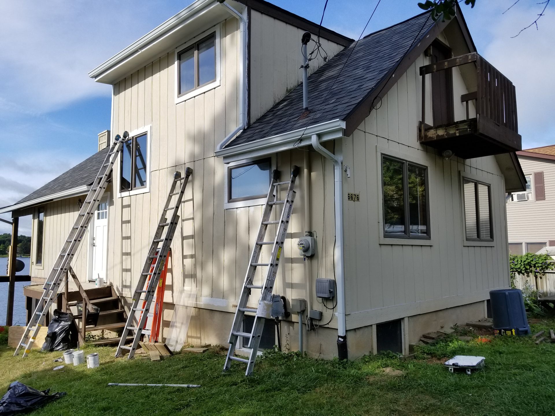 A house is being painted with ladders in front of it.