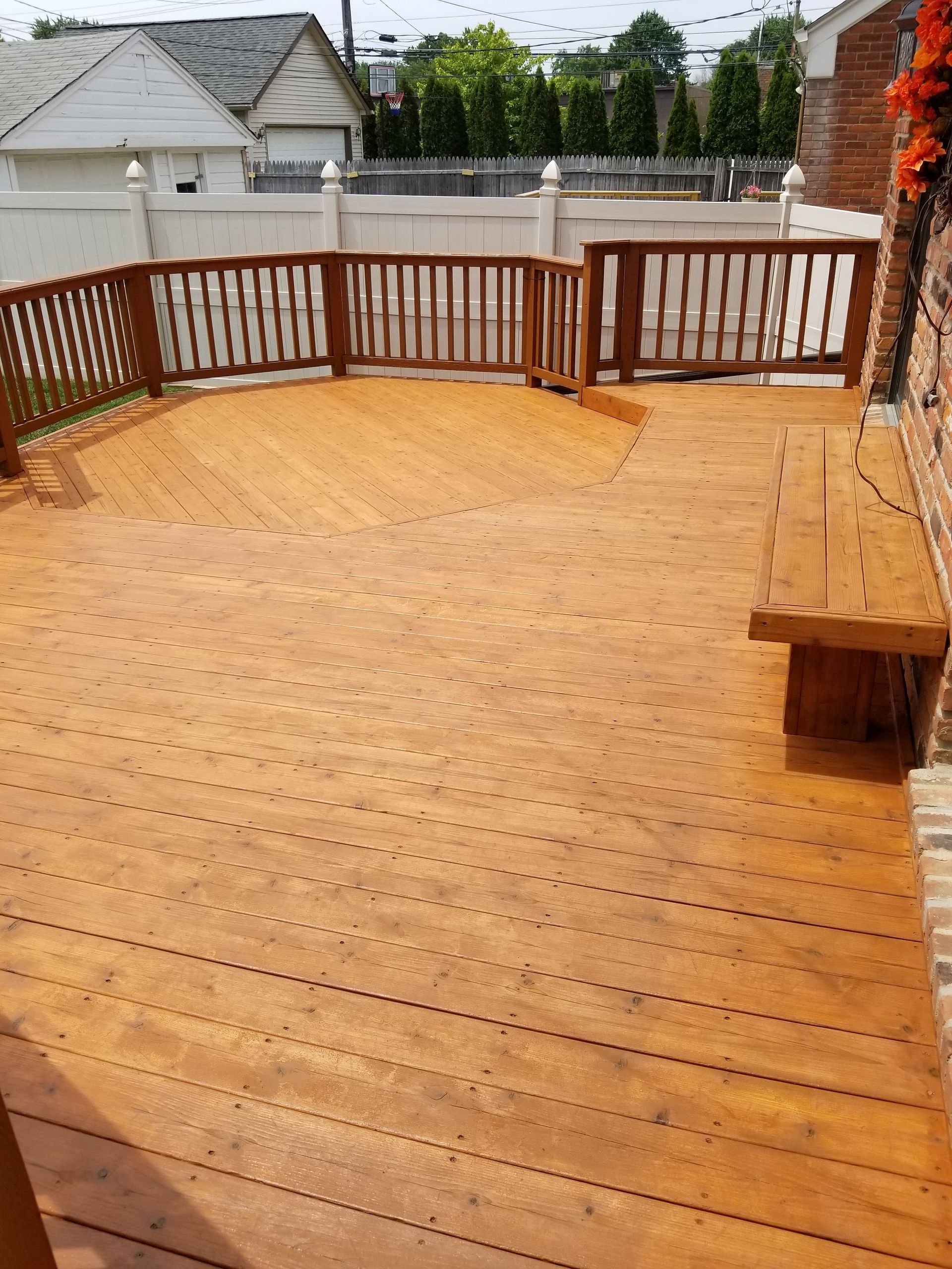 A large wooden deck with a bench and railing.