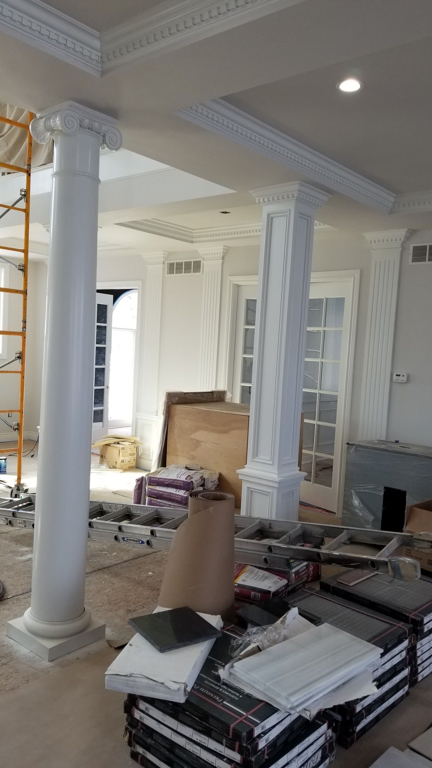 A room with columns and a stack of tiles on the floor.