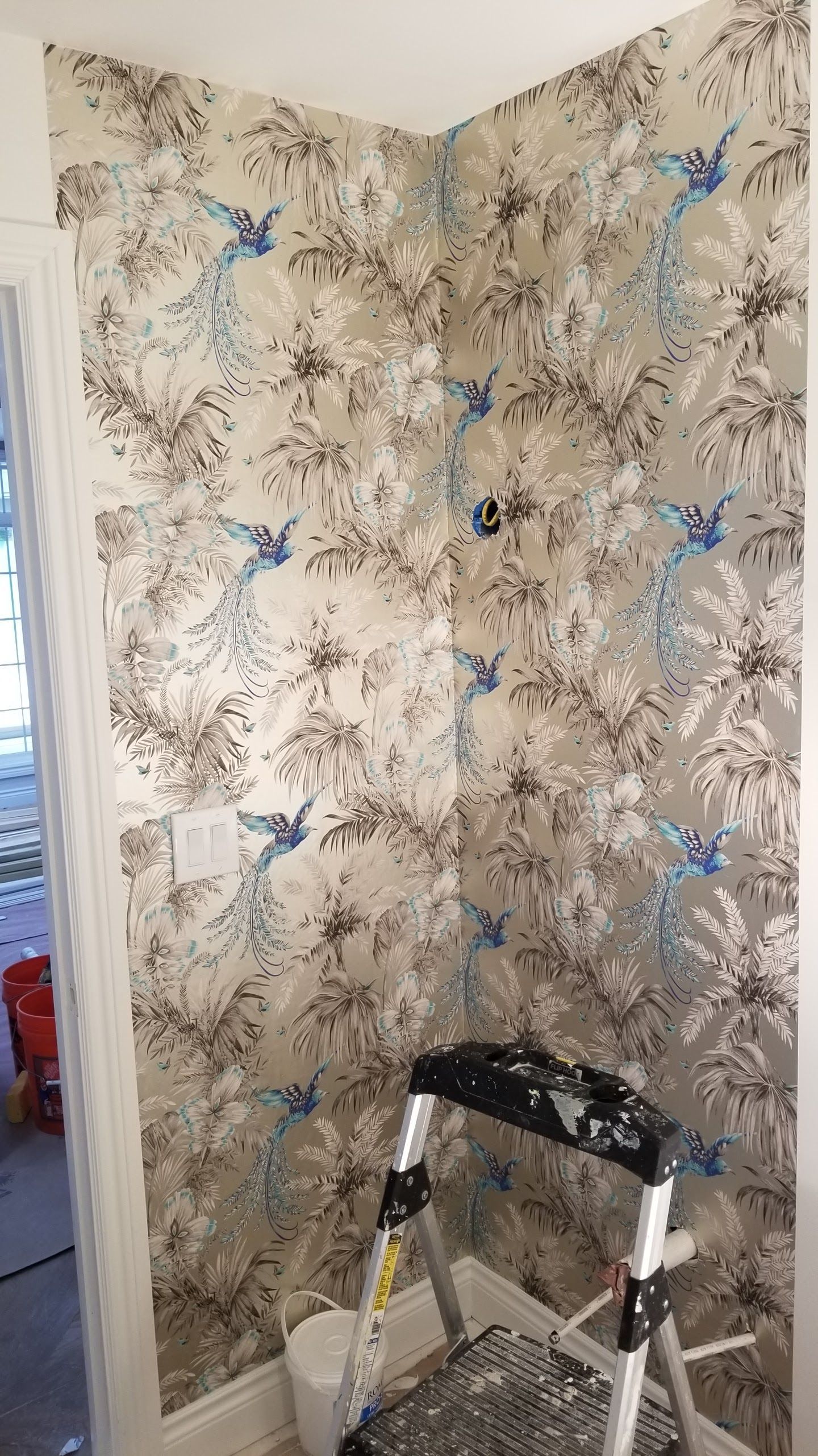 A ladder is sitting in front of a wall with wallpaper on it.