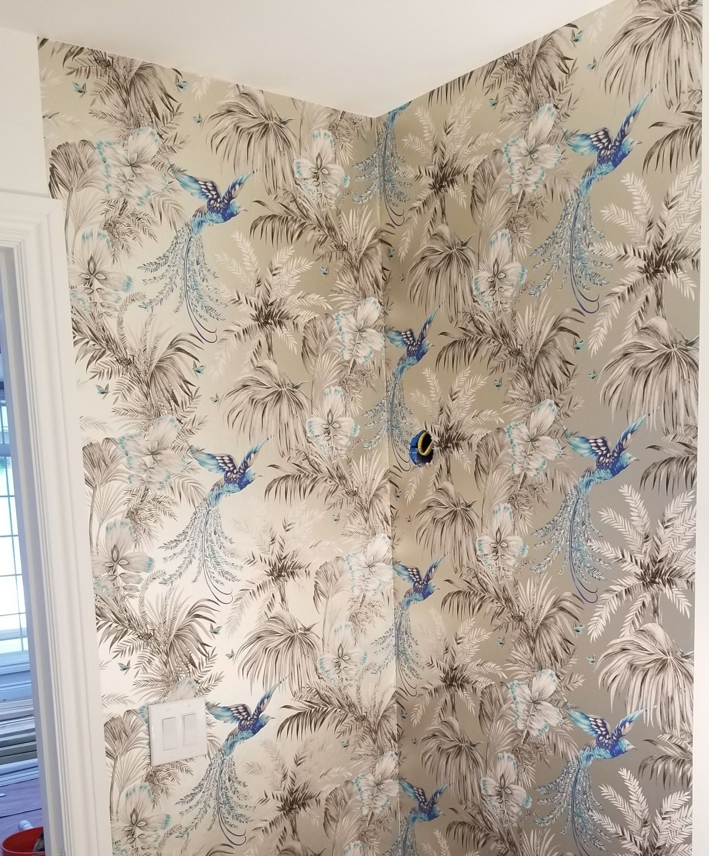 A wall with a pattern of birds and palm trees on it.