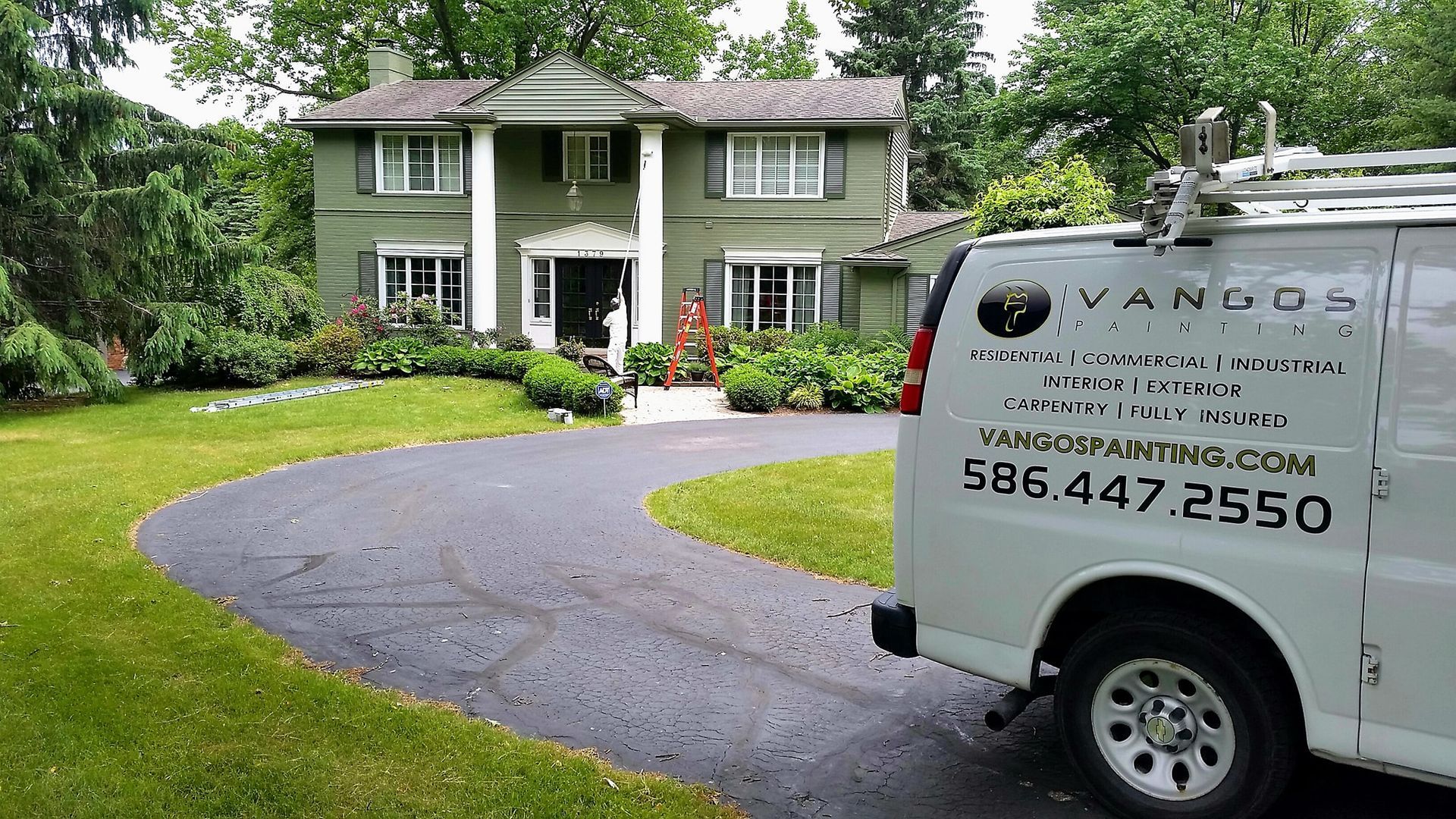 A white van is parked in front of a green house.
