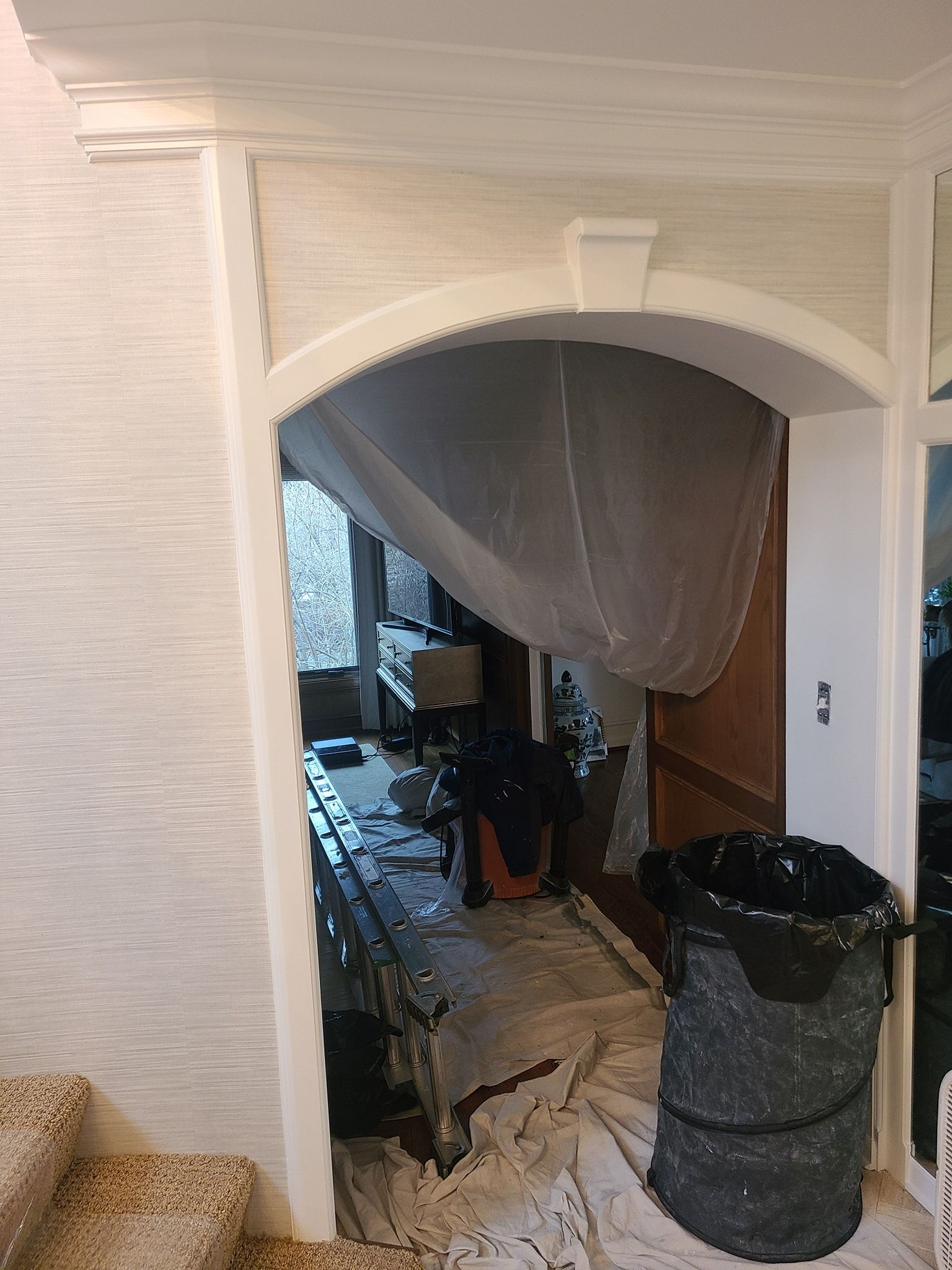 A room with a staircase and a trash can in it.