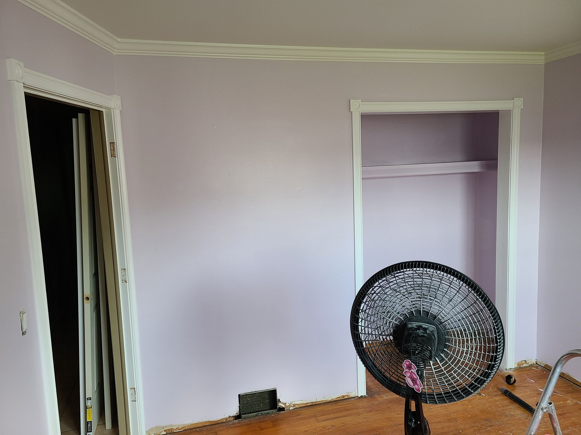 A room with purple walls and a fan on the floor