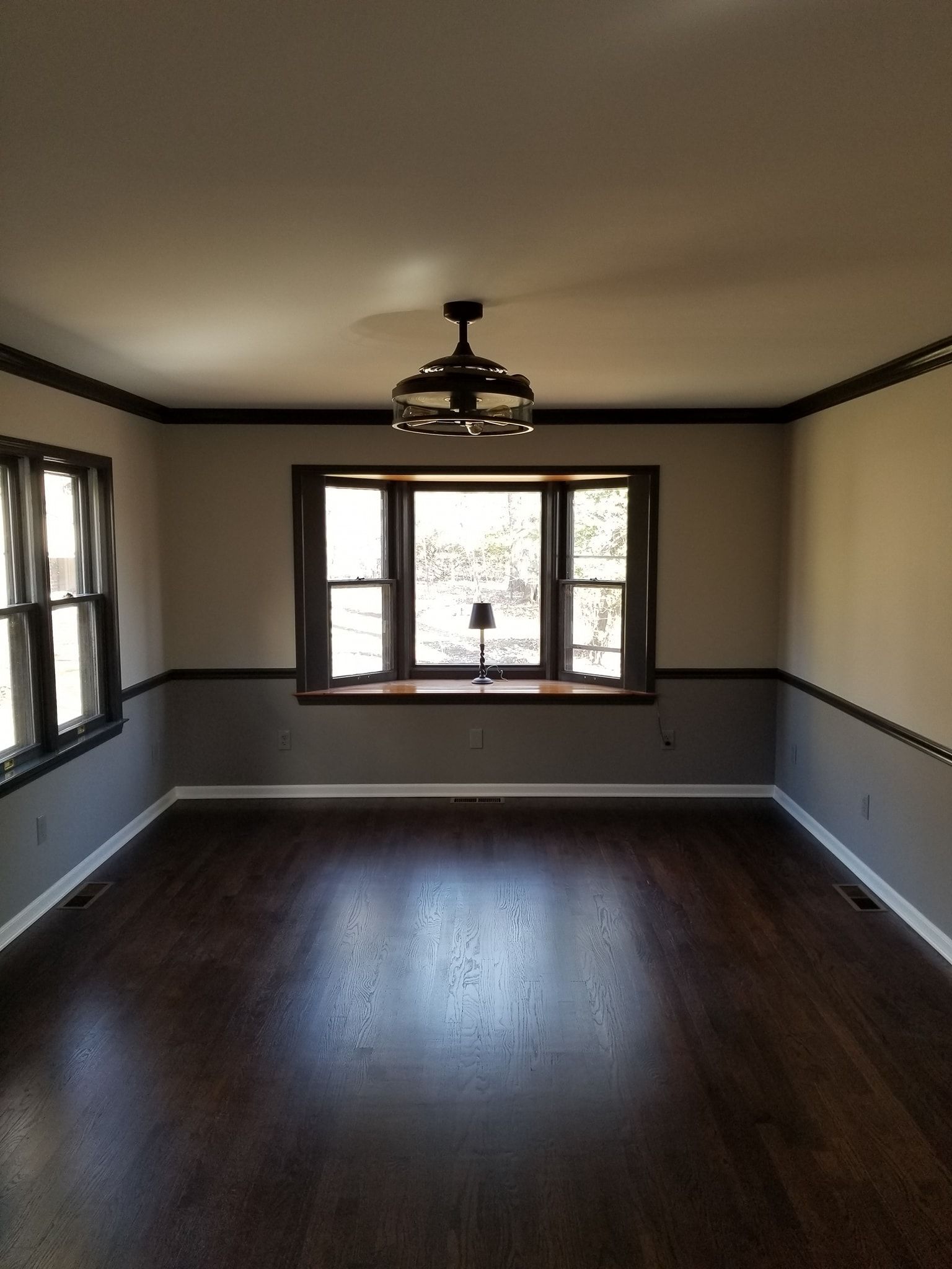 An empty living room with a ceiling fan and a window