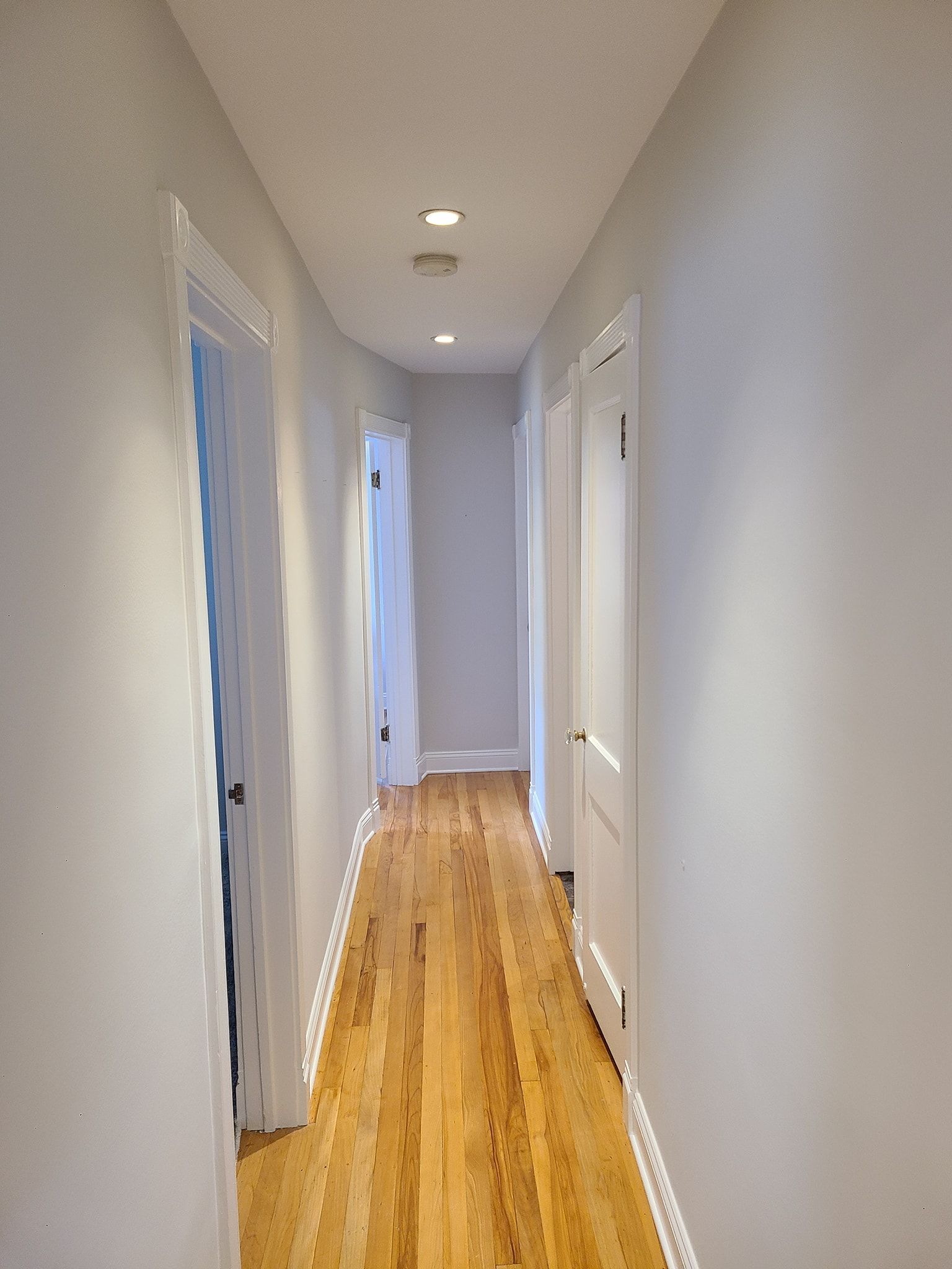A long hallway with wooden floors and white walls
