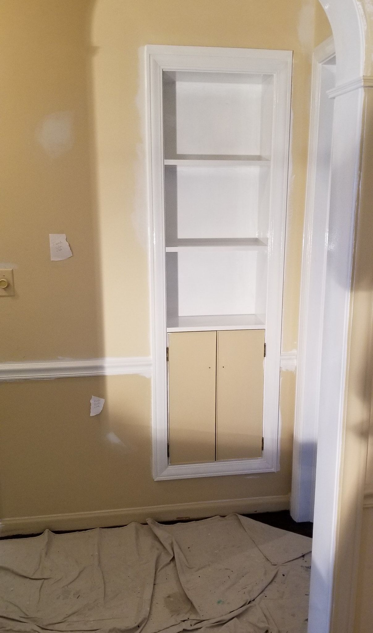 A room with a shelf in the wall and a door.