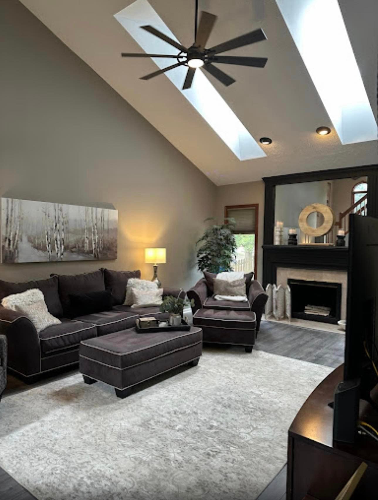 A living room with a ceiling fan , a couch , chairs , and a fireplace.
