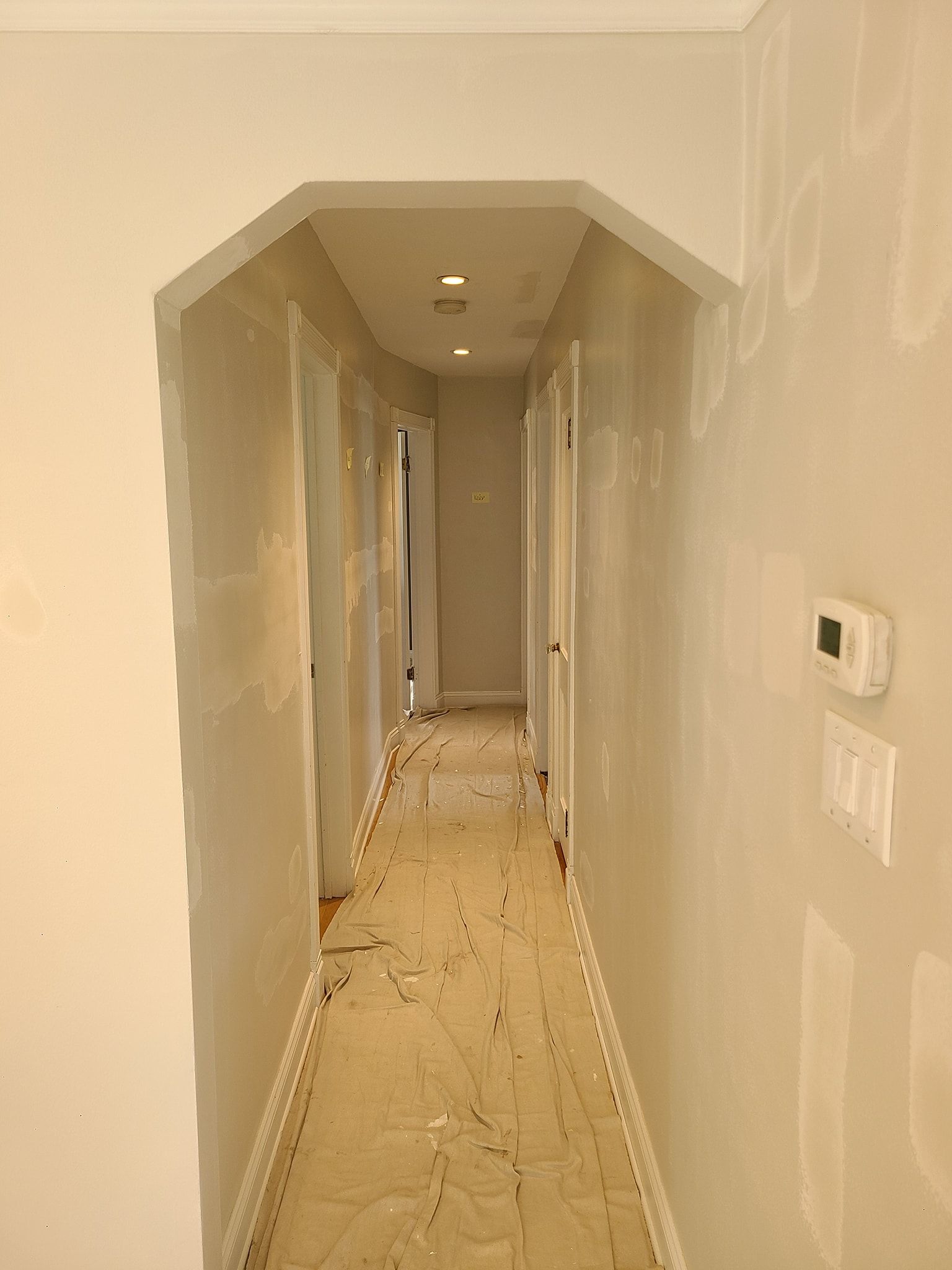 A long hallway with a thermostat on the wall.