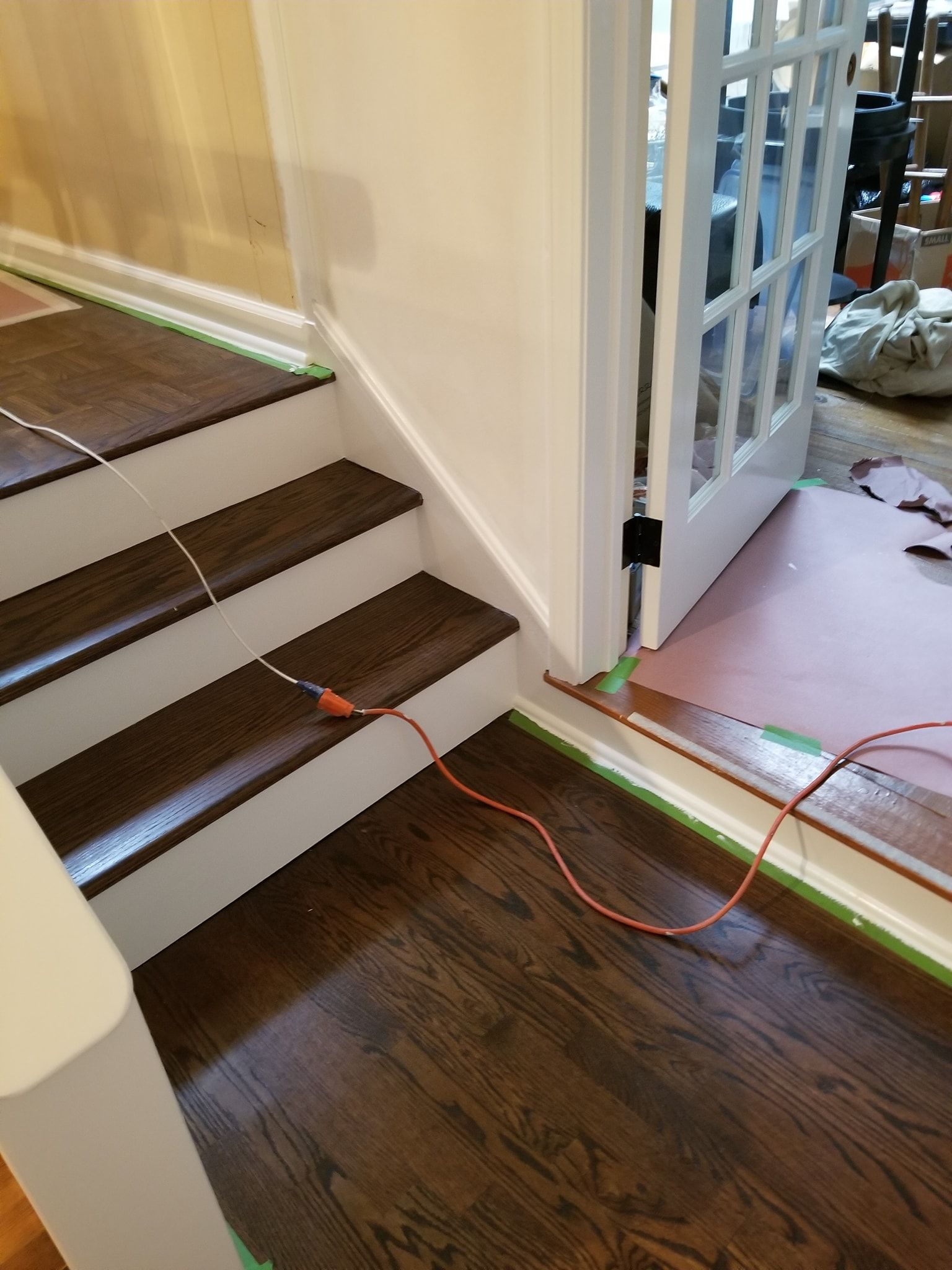 A staircase is being painted in a house with a cord connected to it.