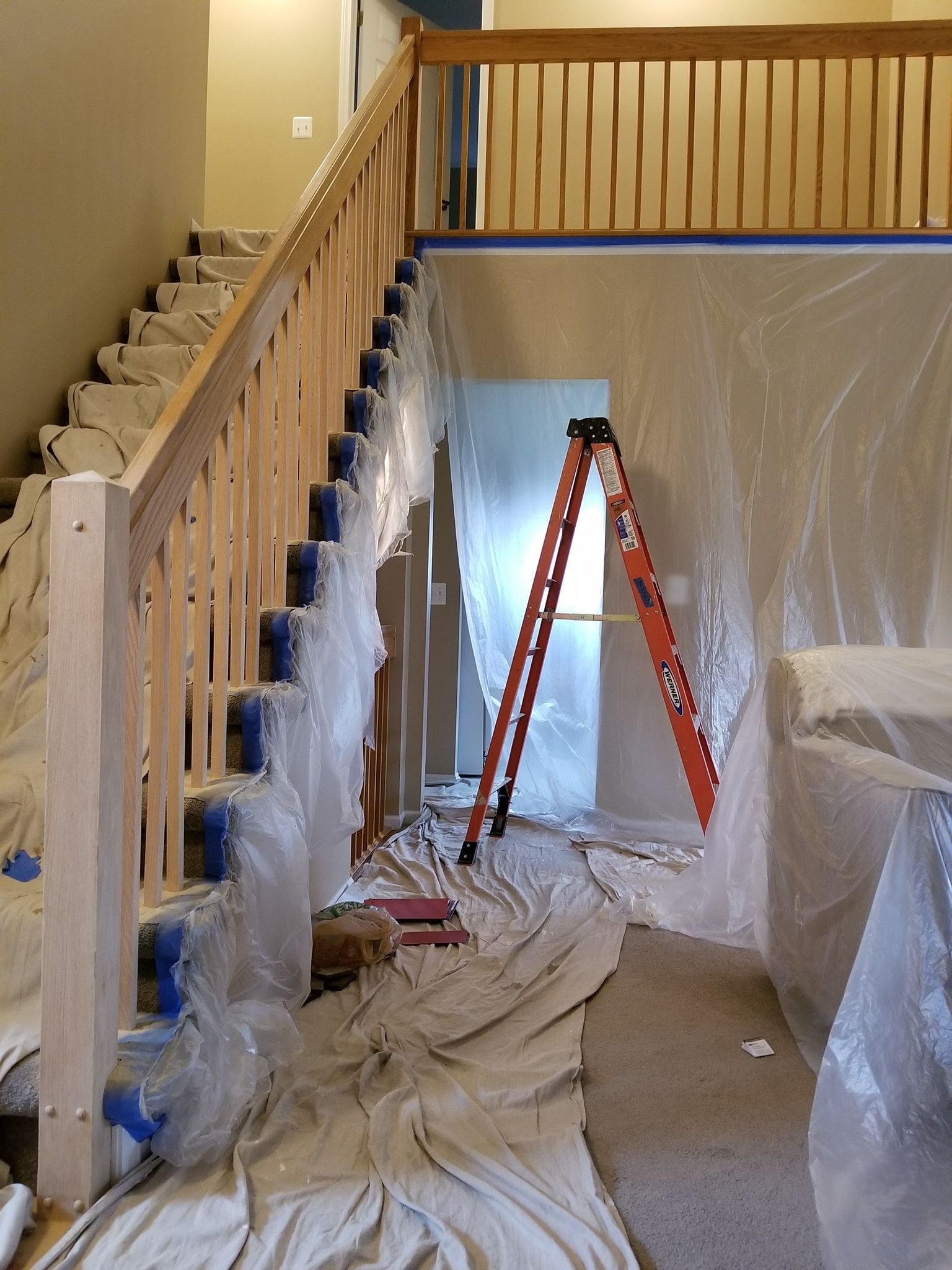 A room with stairs and a ladder covered in plastic