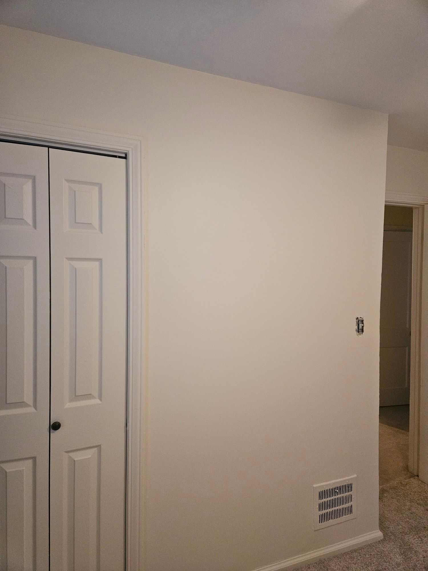 A bedroom with white walls and a closet.