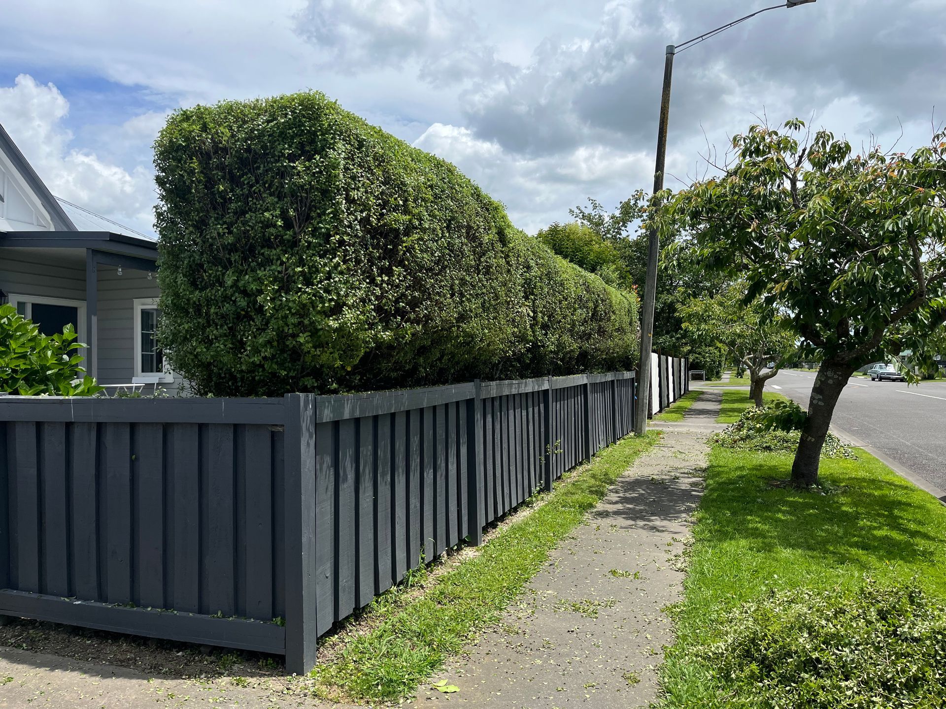 A fence along a sidewalk next to a house.