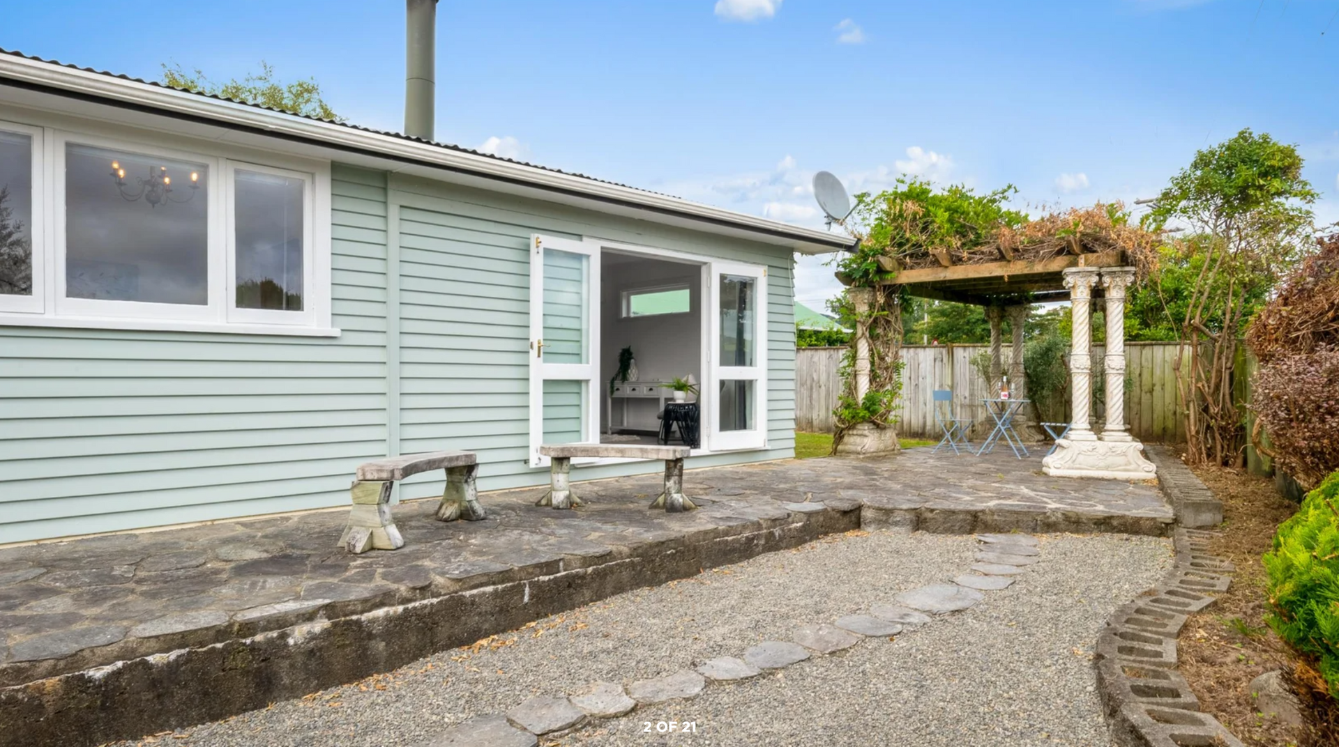 A small house with a patio and a pergola in the backyard.