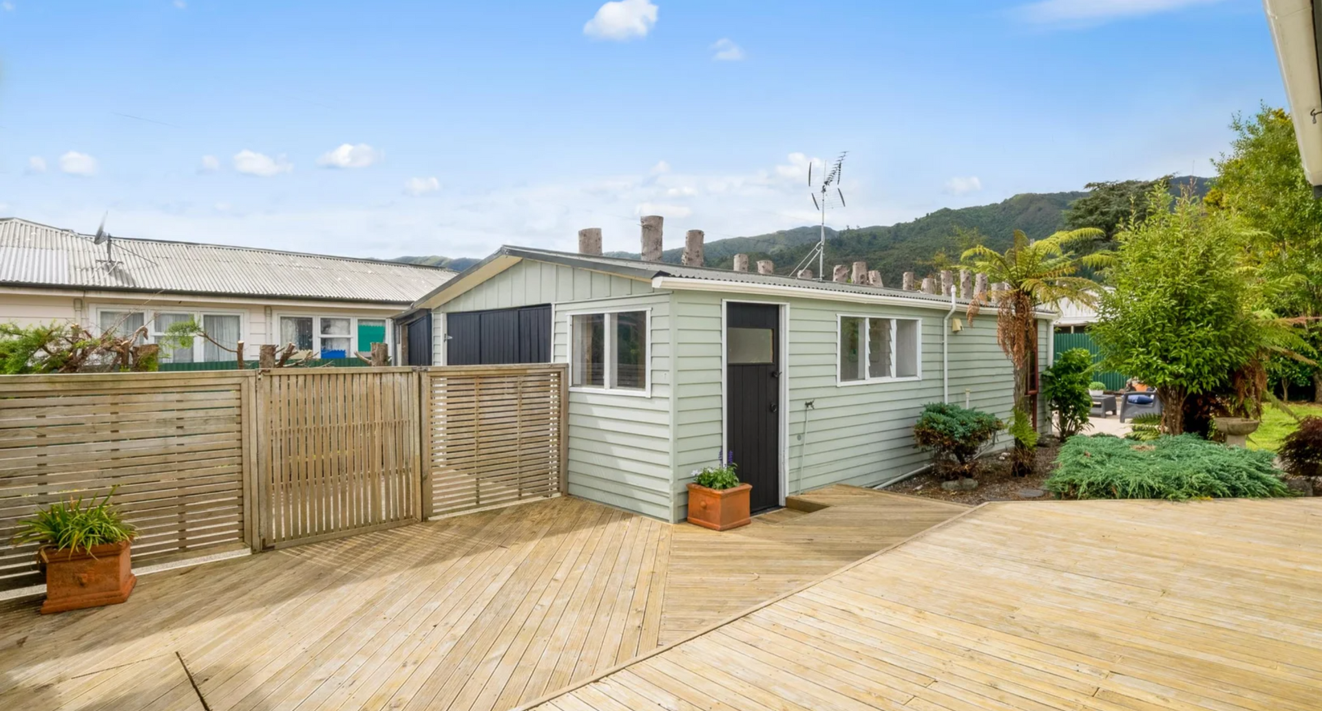 A small white house with a wooden deck in front of it.