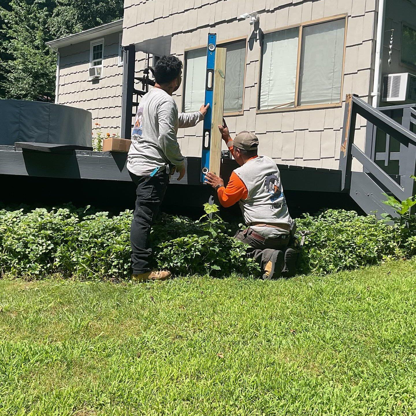 Two men are working on a house with a level.
