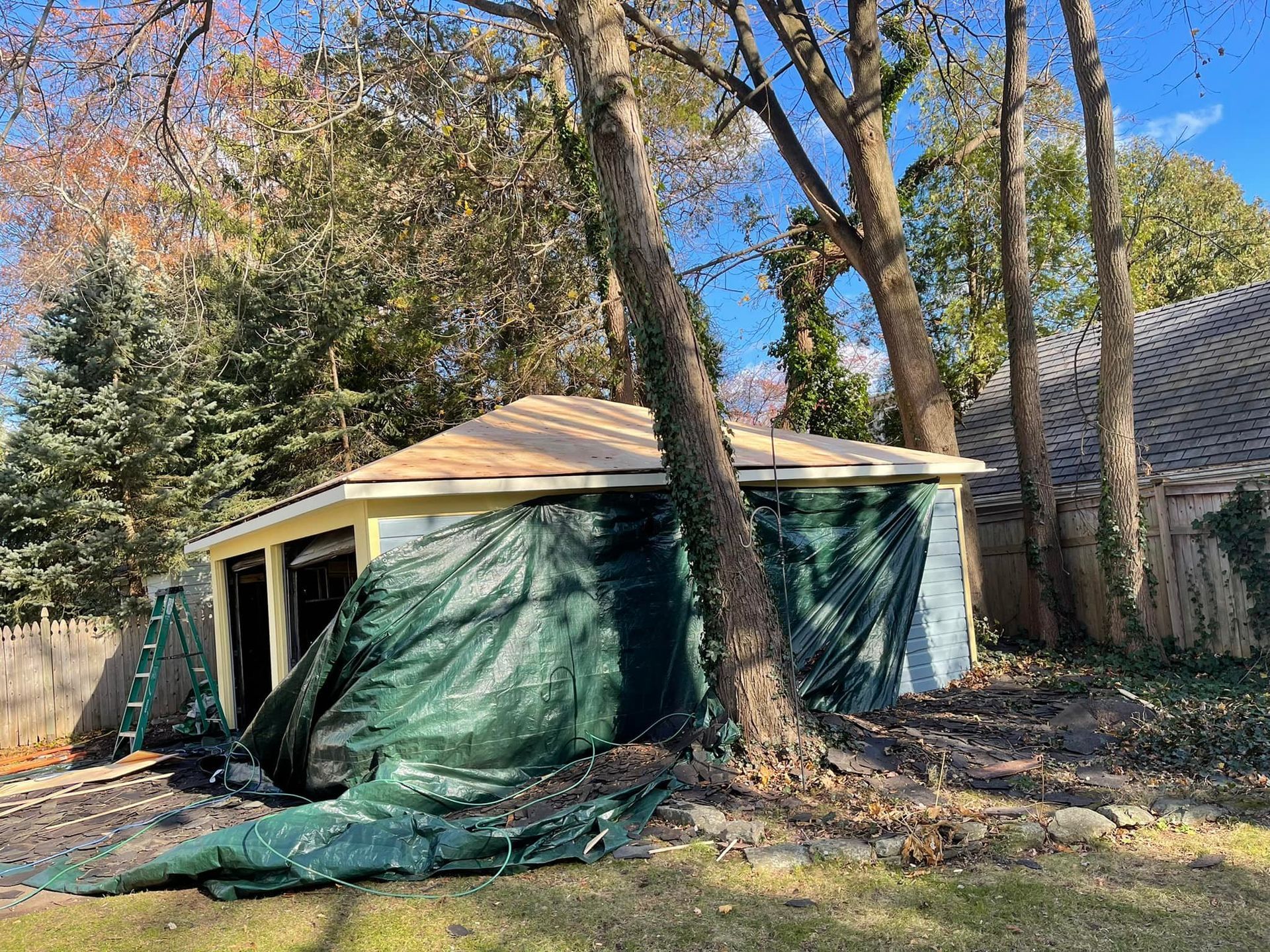 A garage is being built in a backyard surrounded by trees.