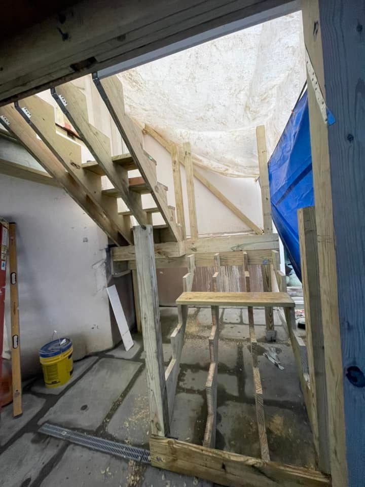 A building under construction with stairs and a blue tarp