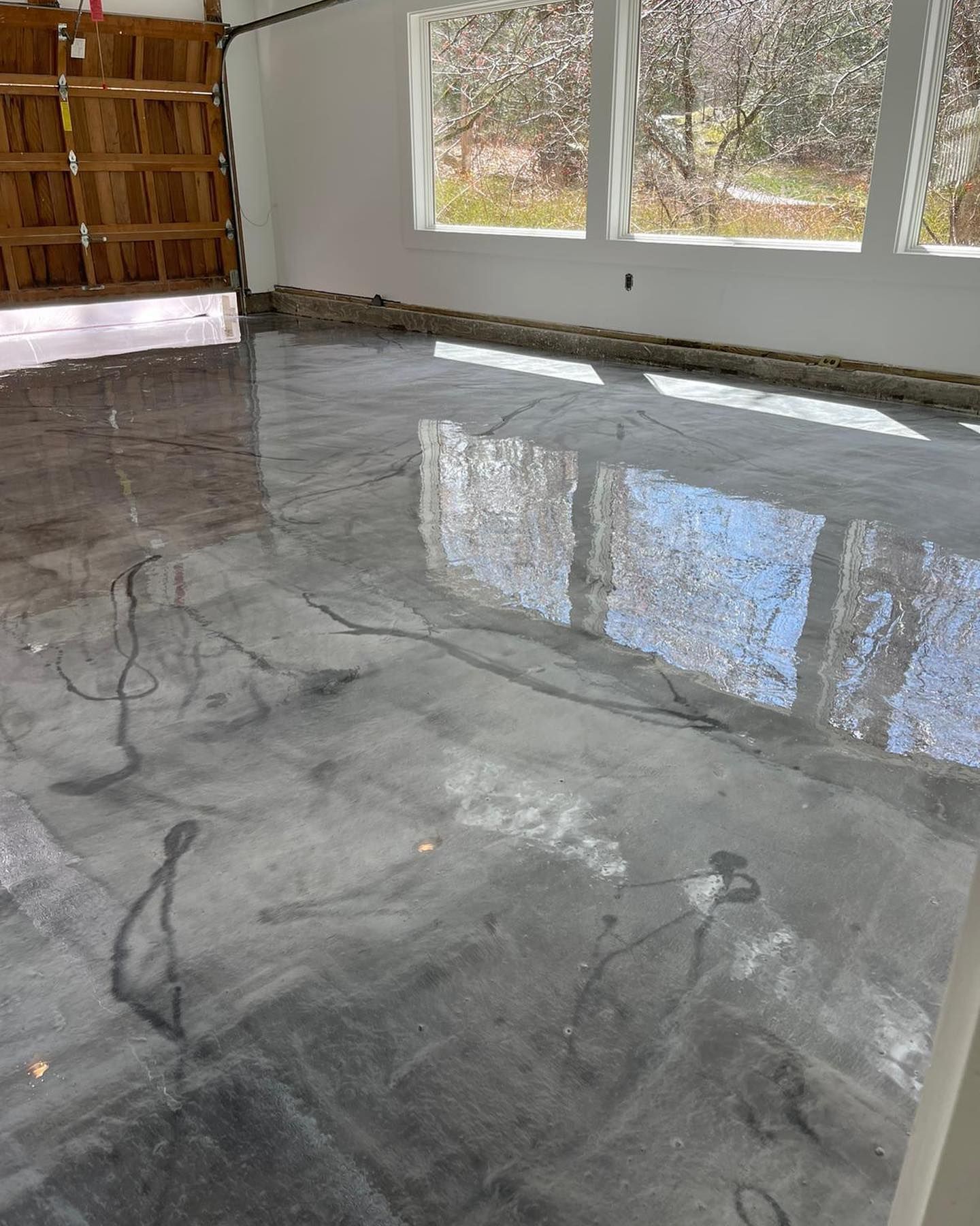 A garage with a shiny metallic floor and a wooden garage door.