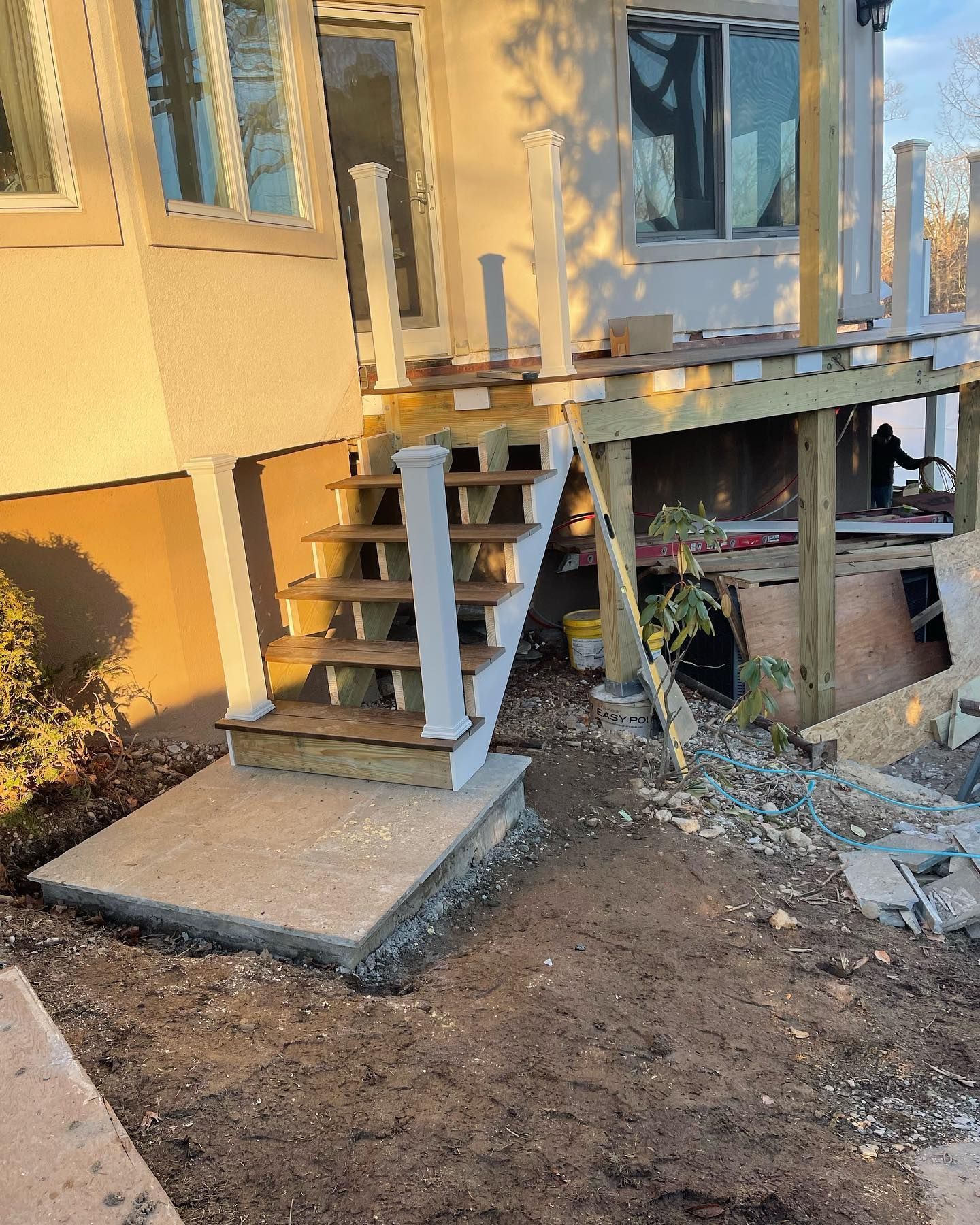 A wooden deck with stairs leading up to it is being built on the side of a house.