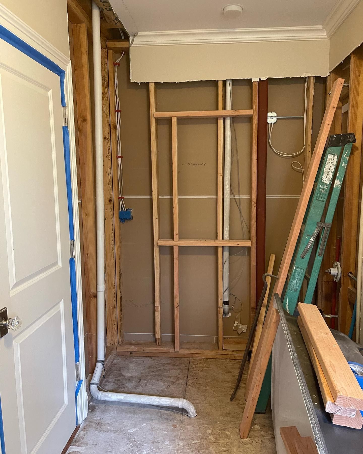 A bathroom under construction with a ladder and pipes.