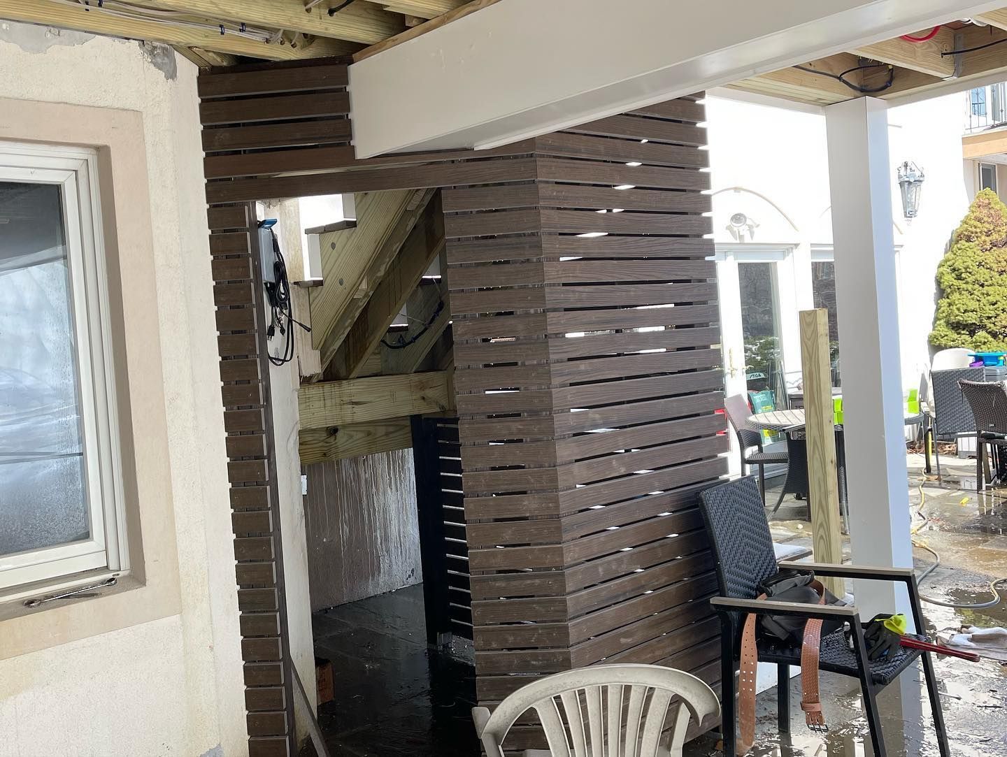 A white chair is sitting on a porch next to a wooden wall.