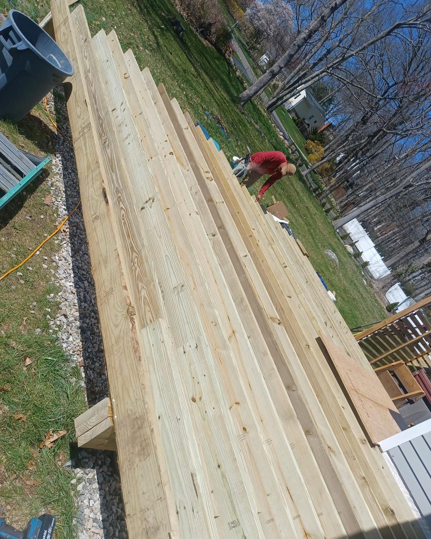 A man is working on a stack of wooden boards in a yard.