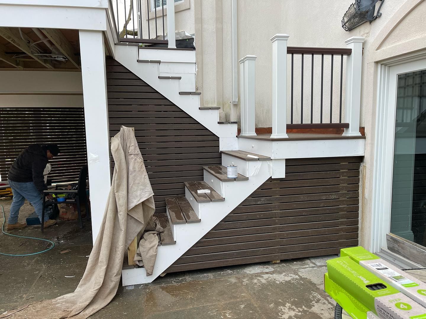 A man is working on a staircase outside of a house.