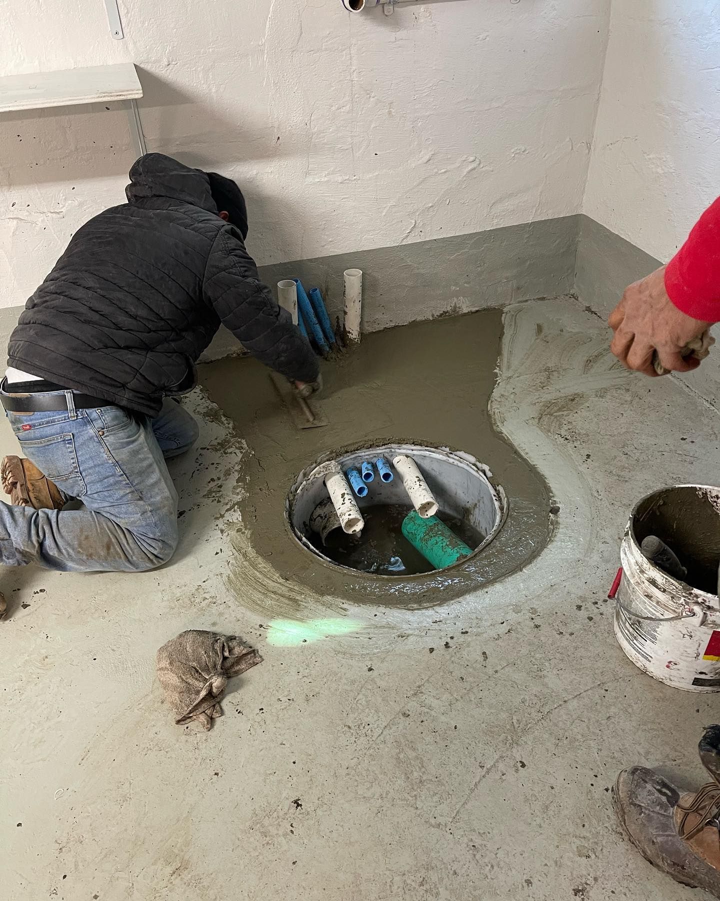 A man is kneeling down in front of a hole in the floor.
