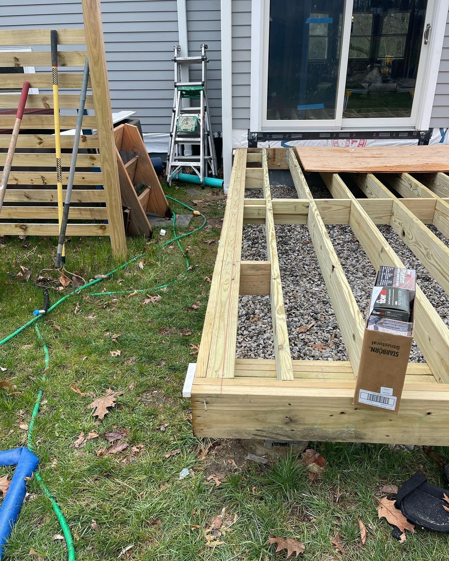 A wooden deck is being built in the backyard of a house.