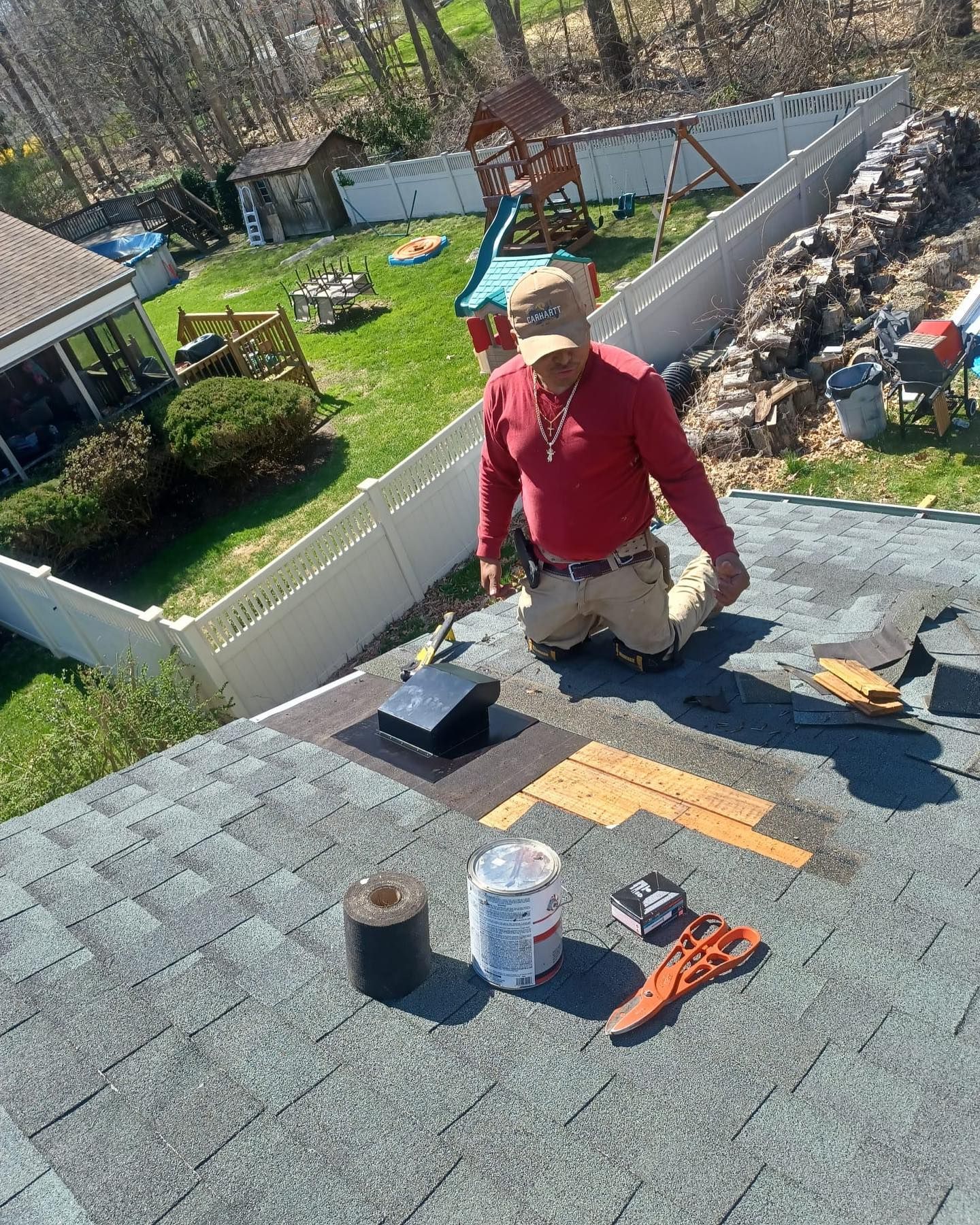 A man is kneeling on the roof of a house.