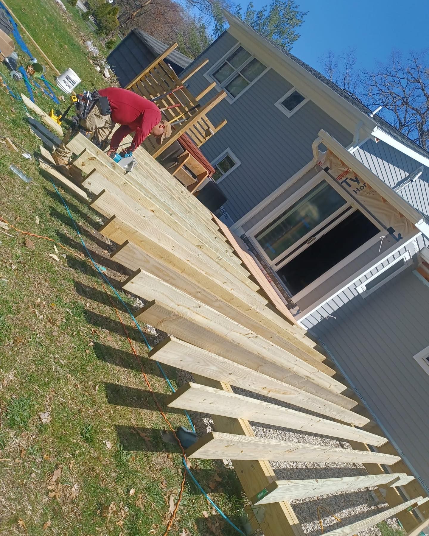 A man is working on a wooden deck in front of a house.
