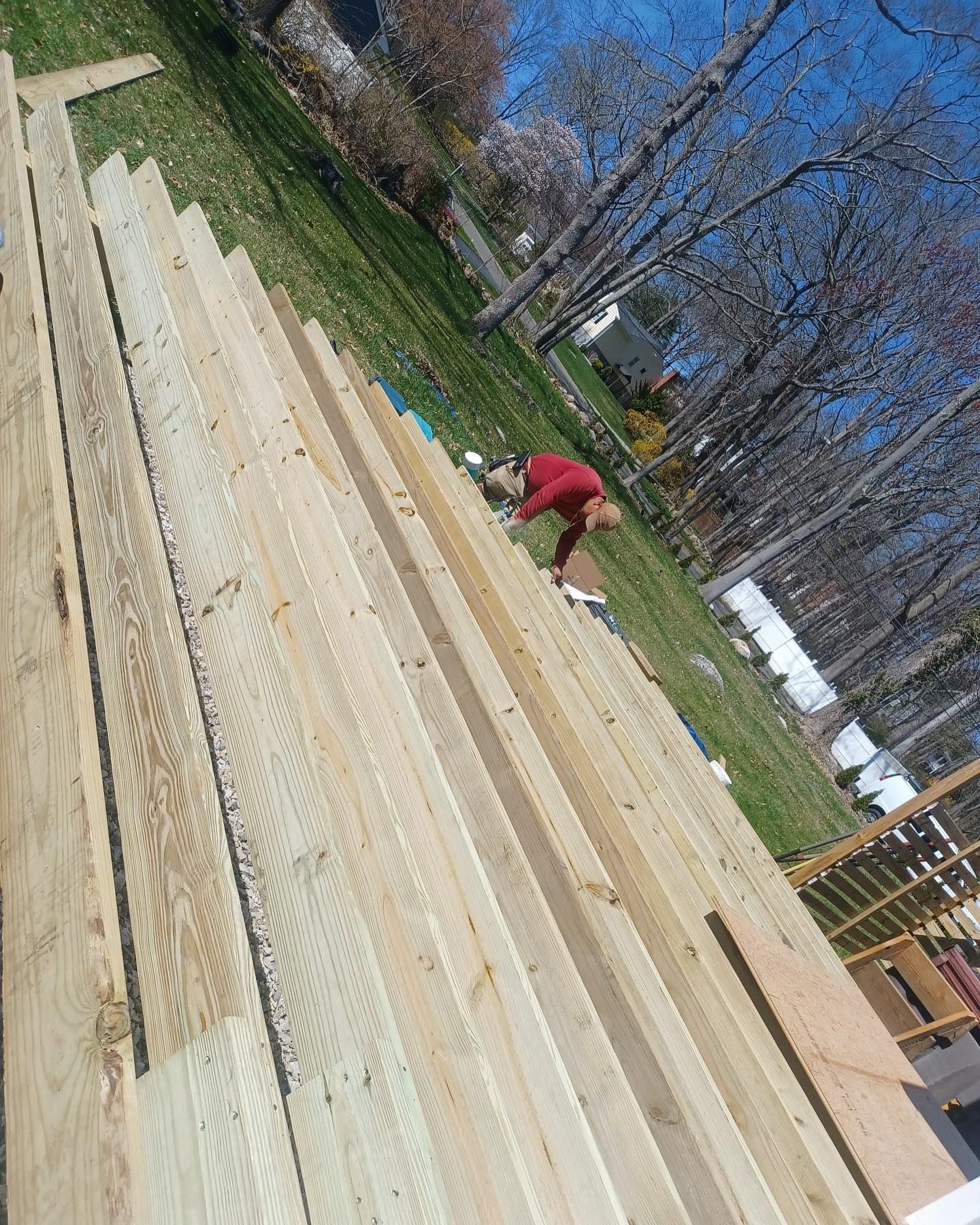A person is working on a pile of wood in a yard.