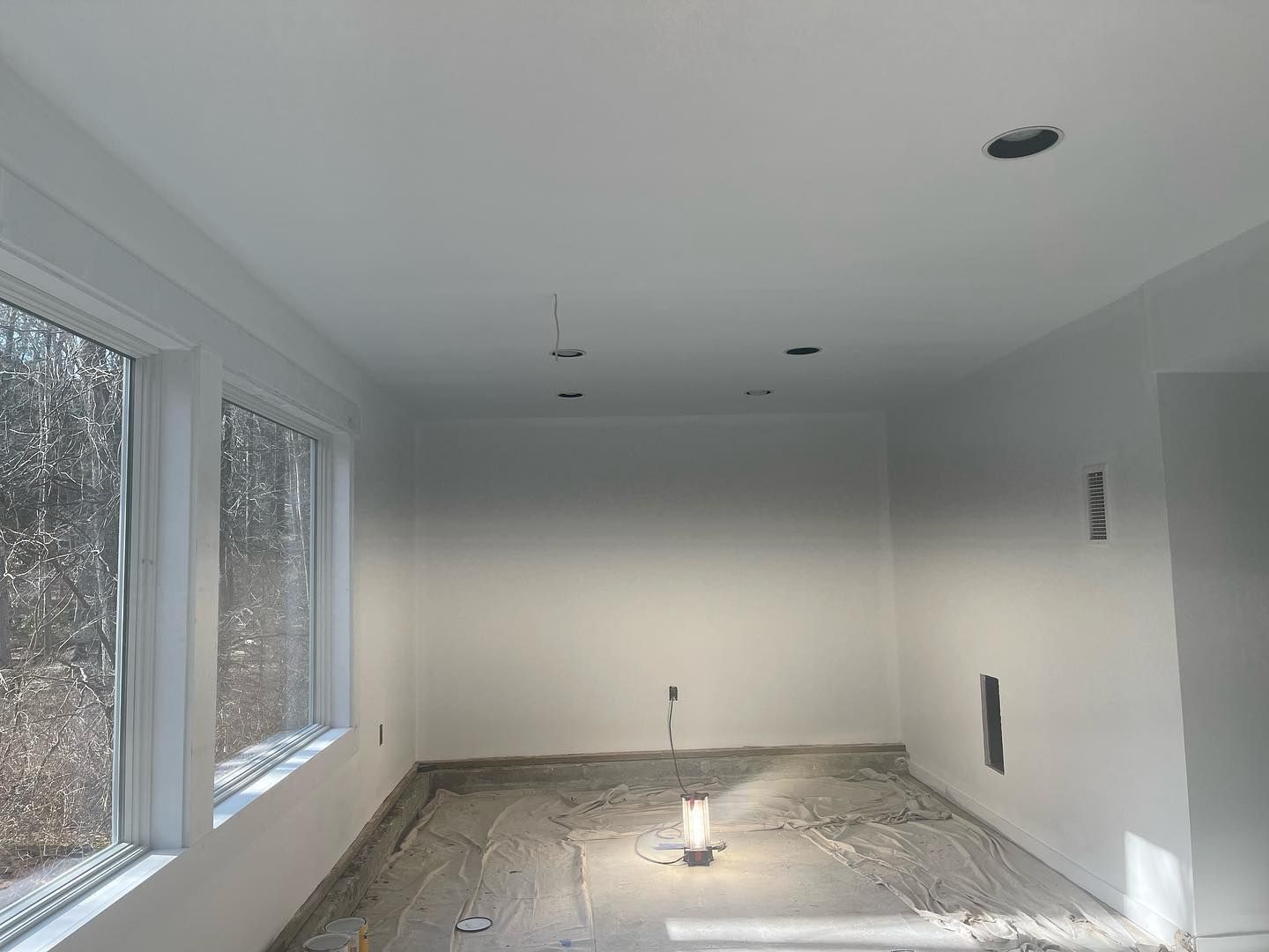A room with a lot of windows and a light on the floor.