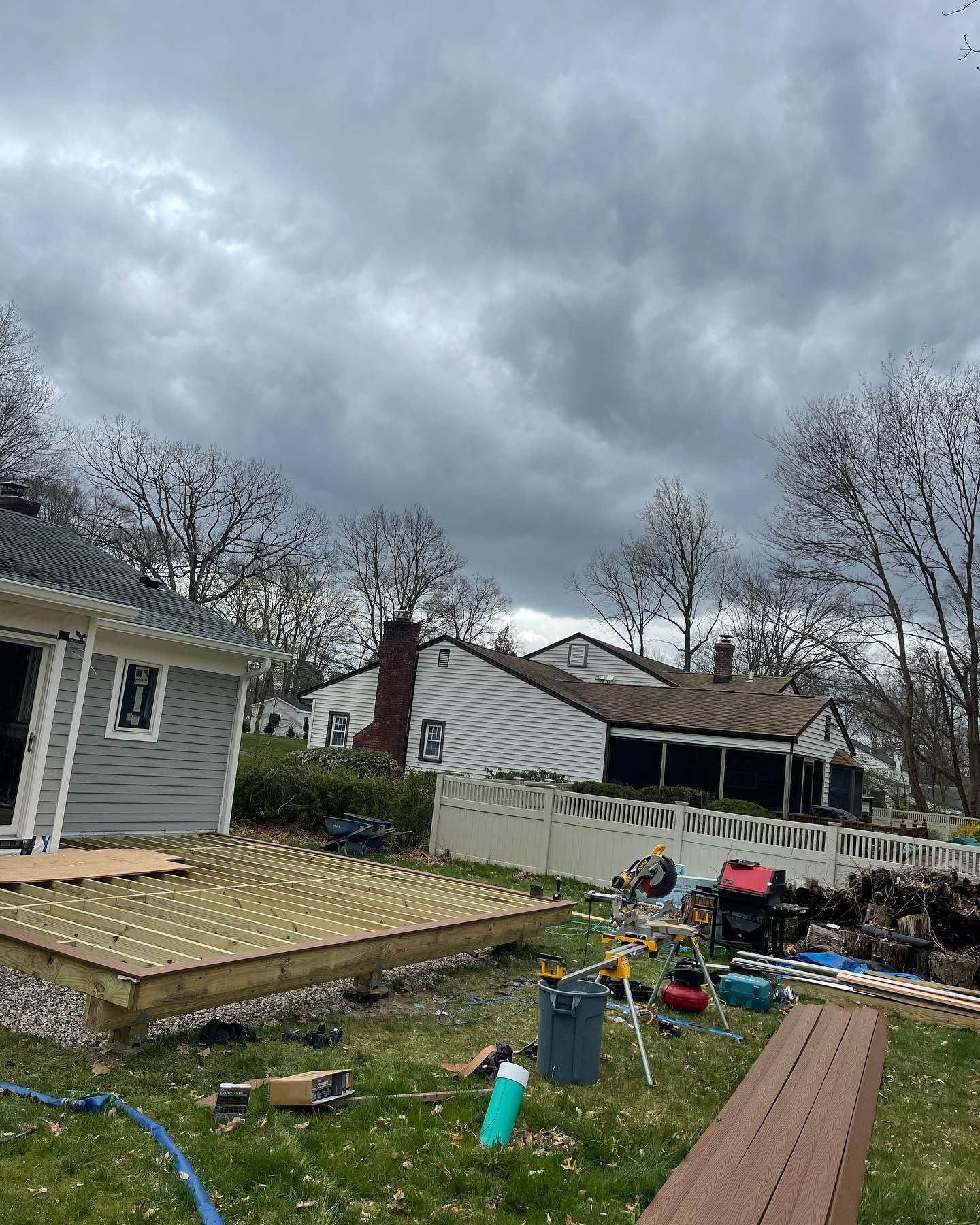 A wooden deck is being built in the backyard of a house.