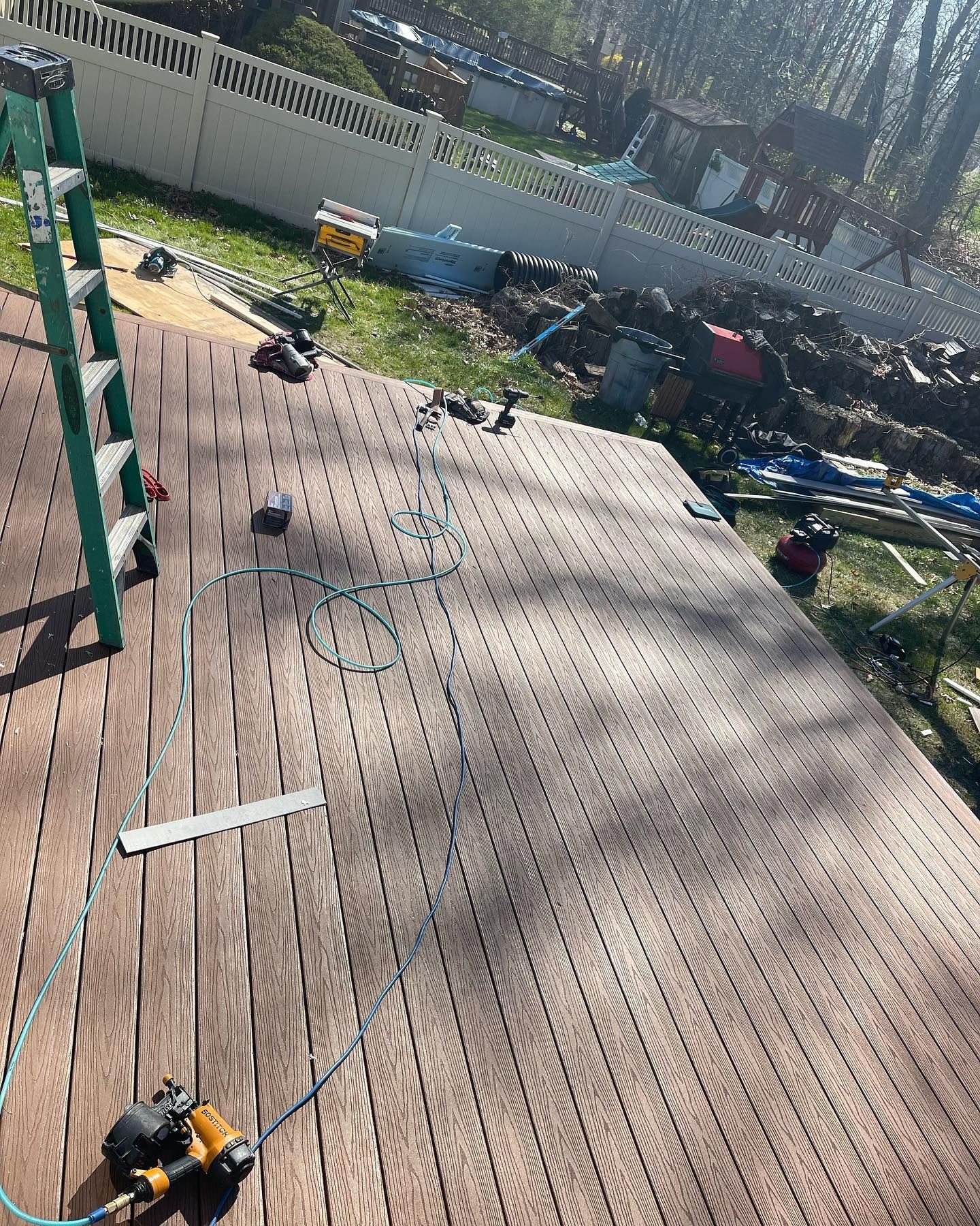 A wooden deck is being built with a ladder and tools.