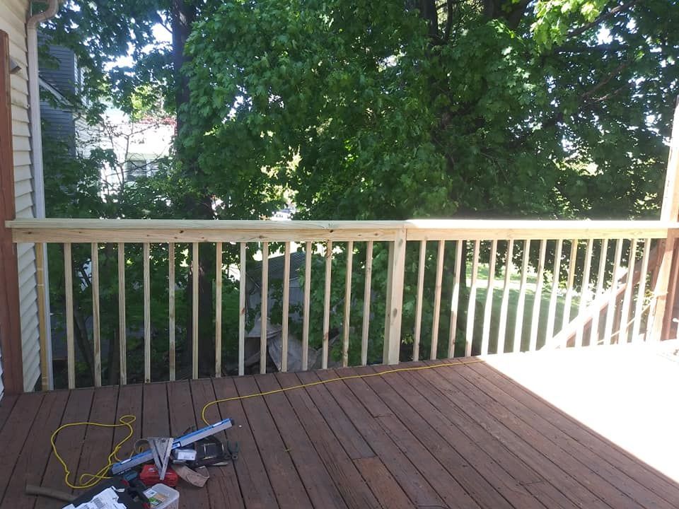 A wooden deck with a railing and trees in the background