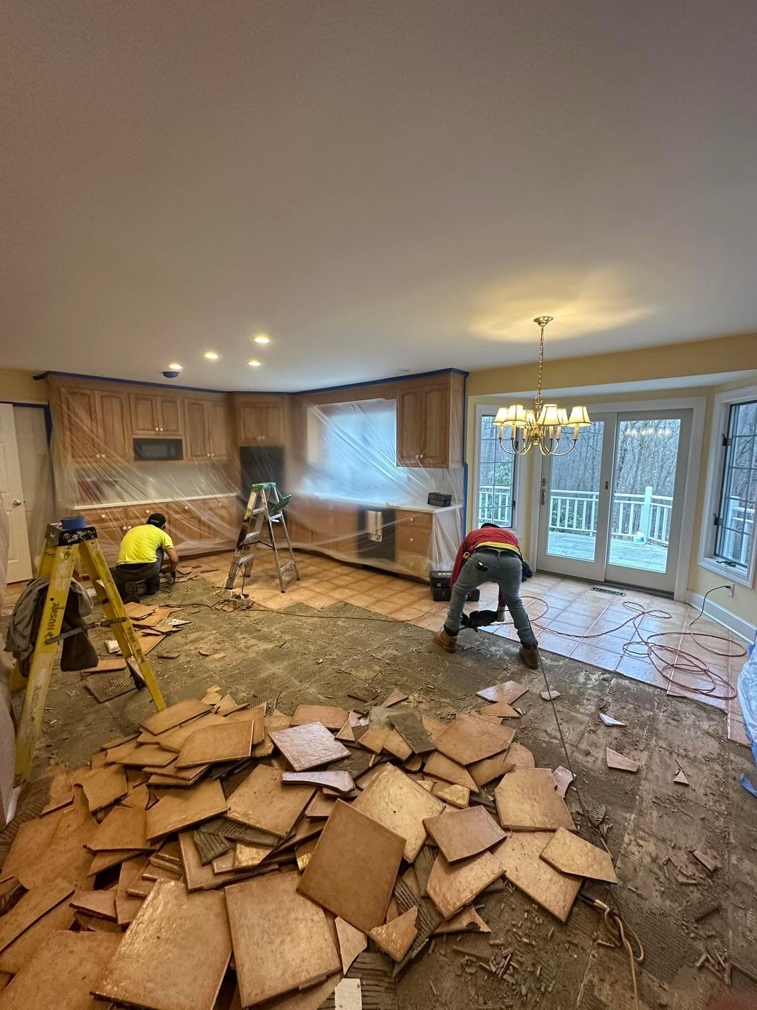 A group of men are working on a wooden floor in a living room.