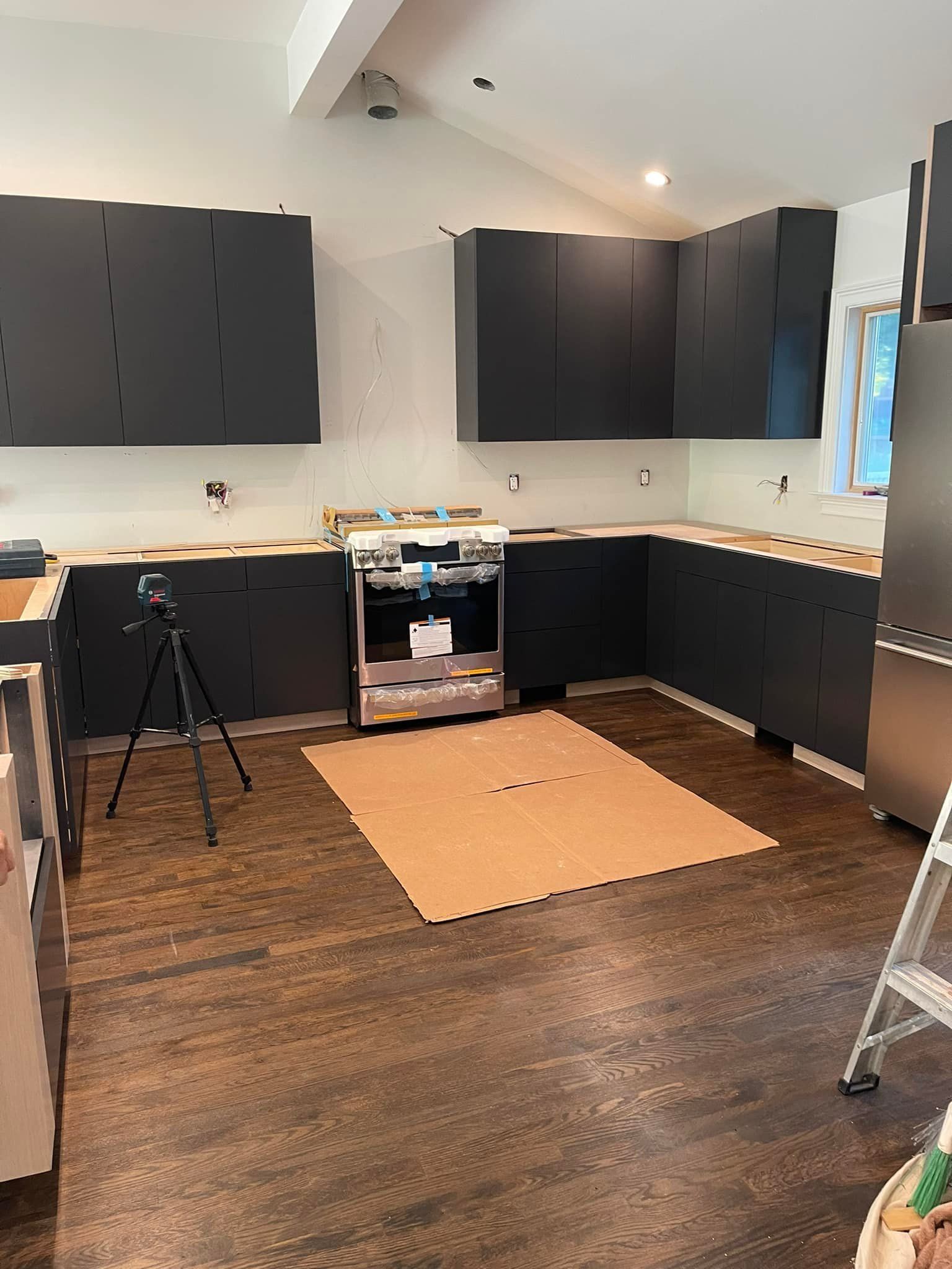 A kitchen with black cabinets and stainless steel appliances is being remodeled.